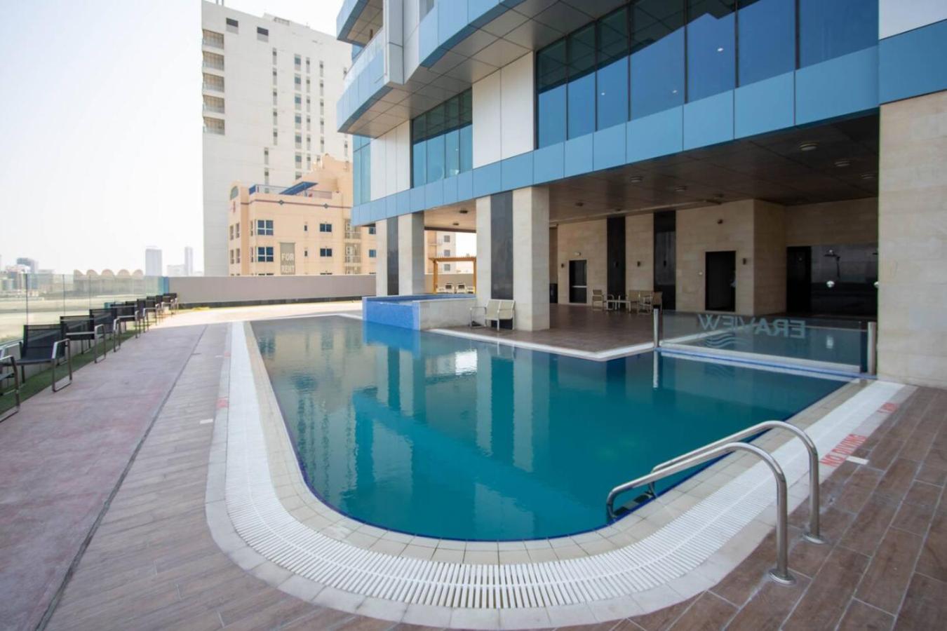 a swimming pool in front of a building at Seaview White 1Br Balcony in Manama