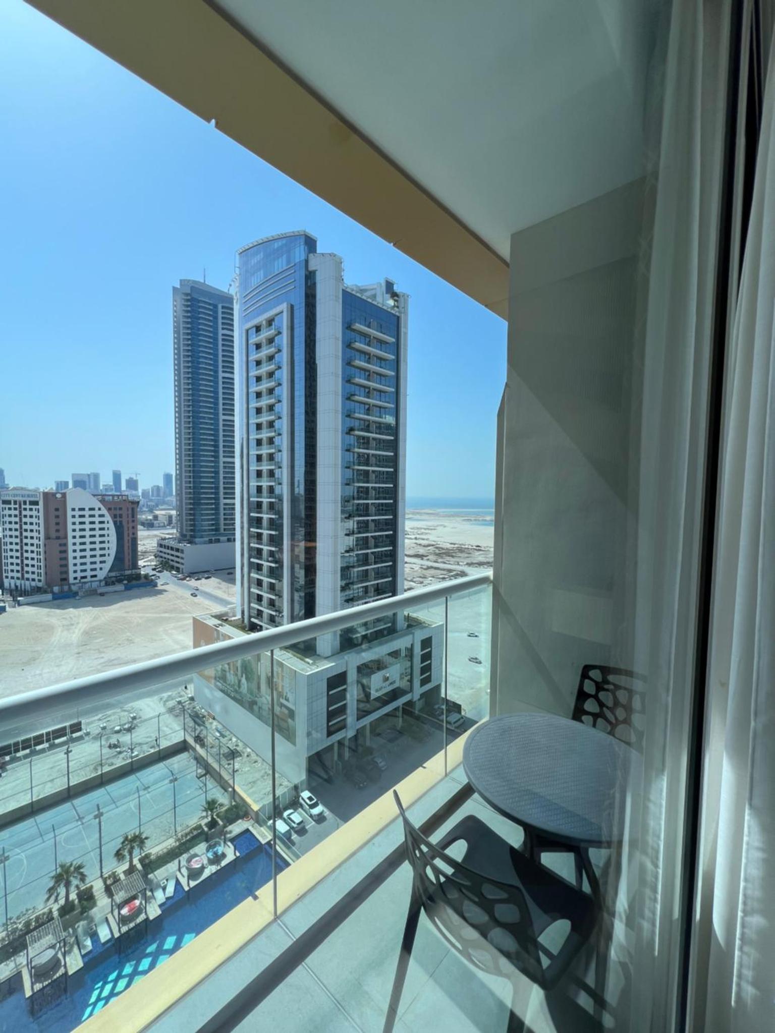 a balcony with a chair and a view of a city at Cozy Stay in Manama