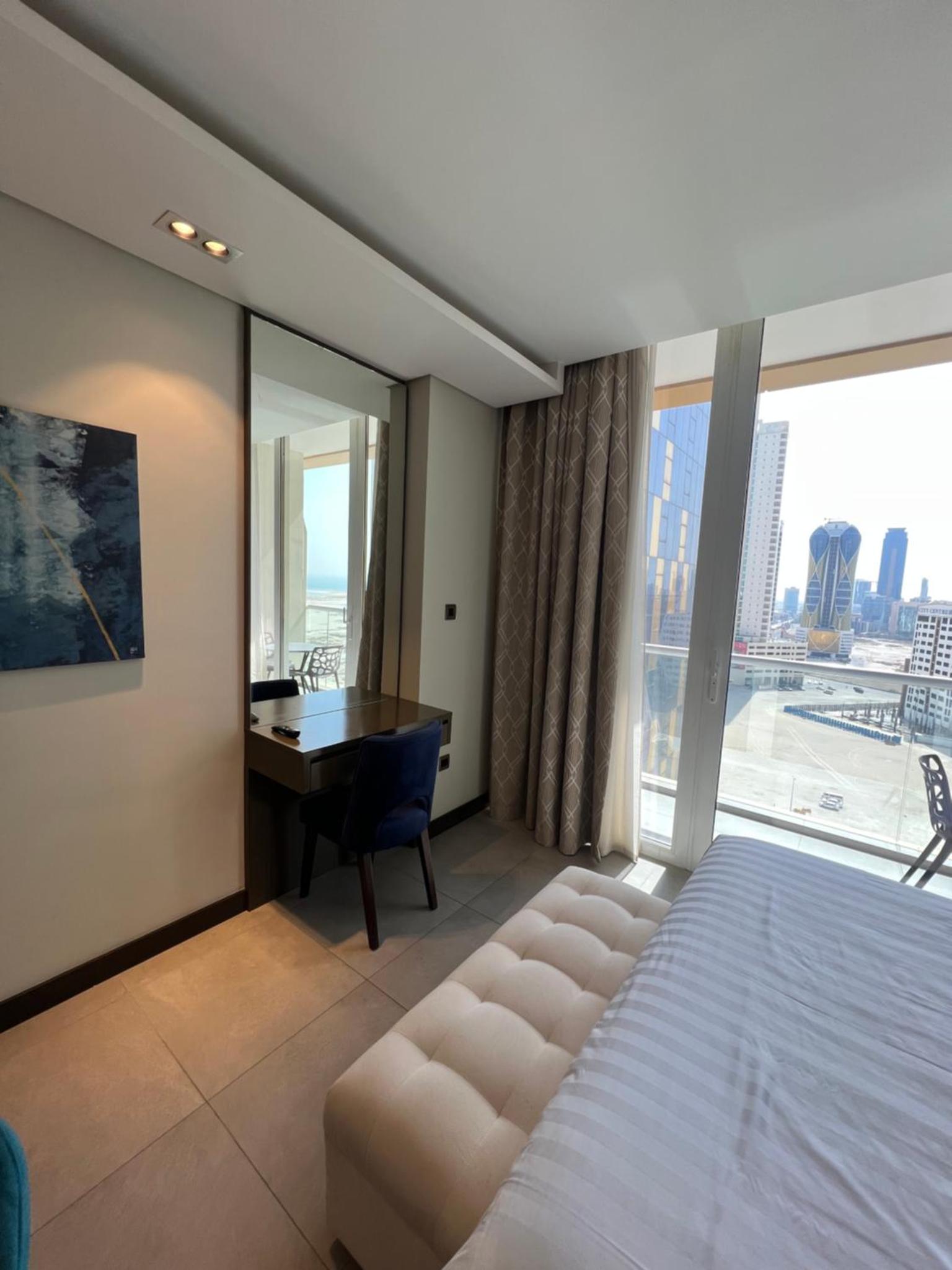 a bedroom with a bed and a desk and a window at Cozy Stay in Manama +48 photos