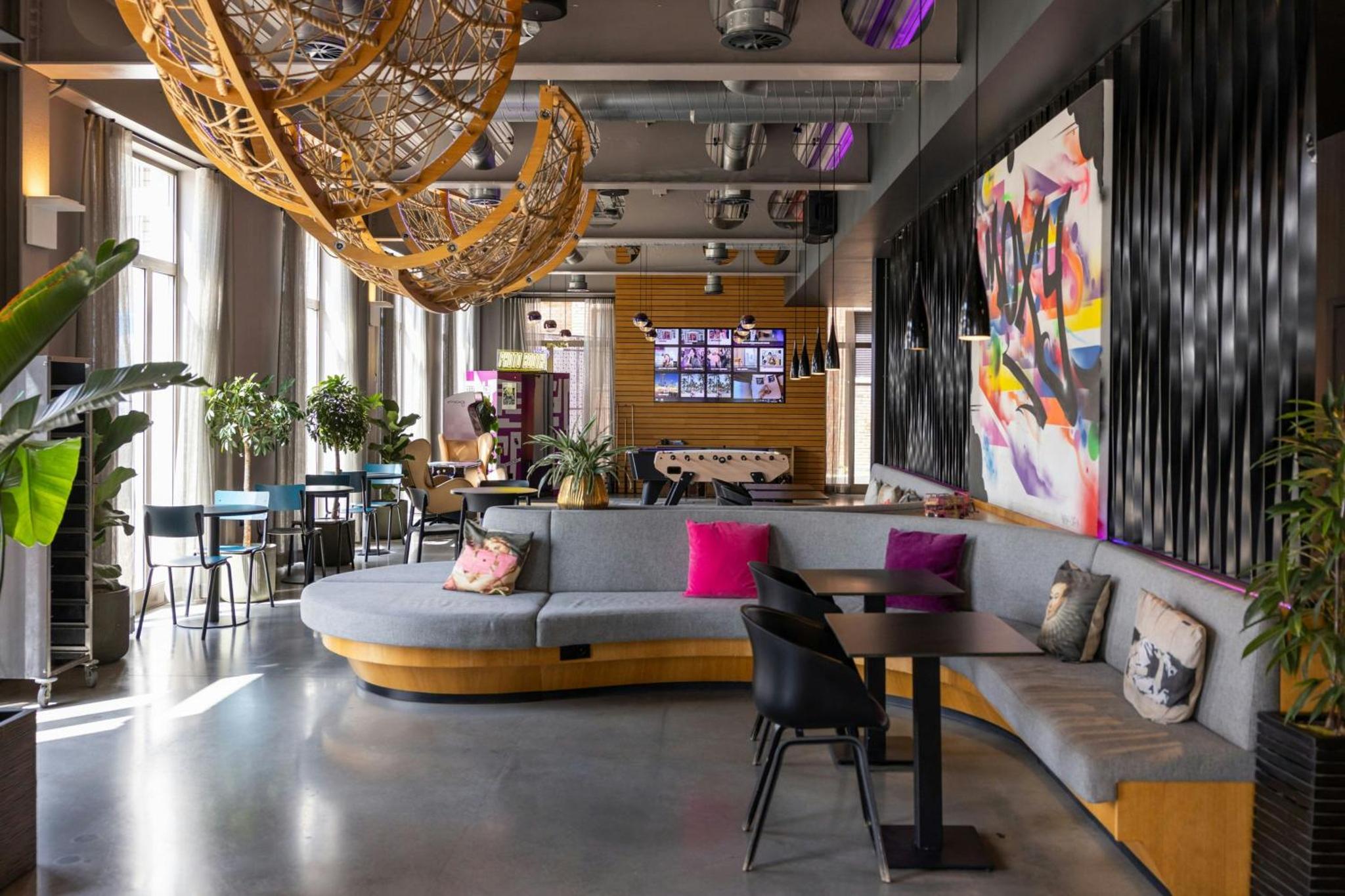 a lobby with a couch and tables and a chandelier at Moxy London Excel in London