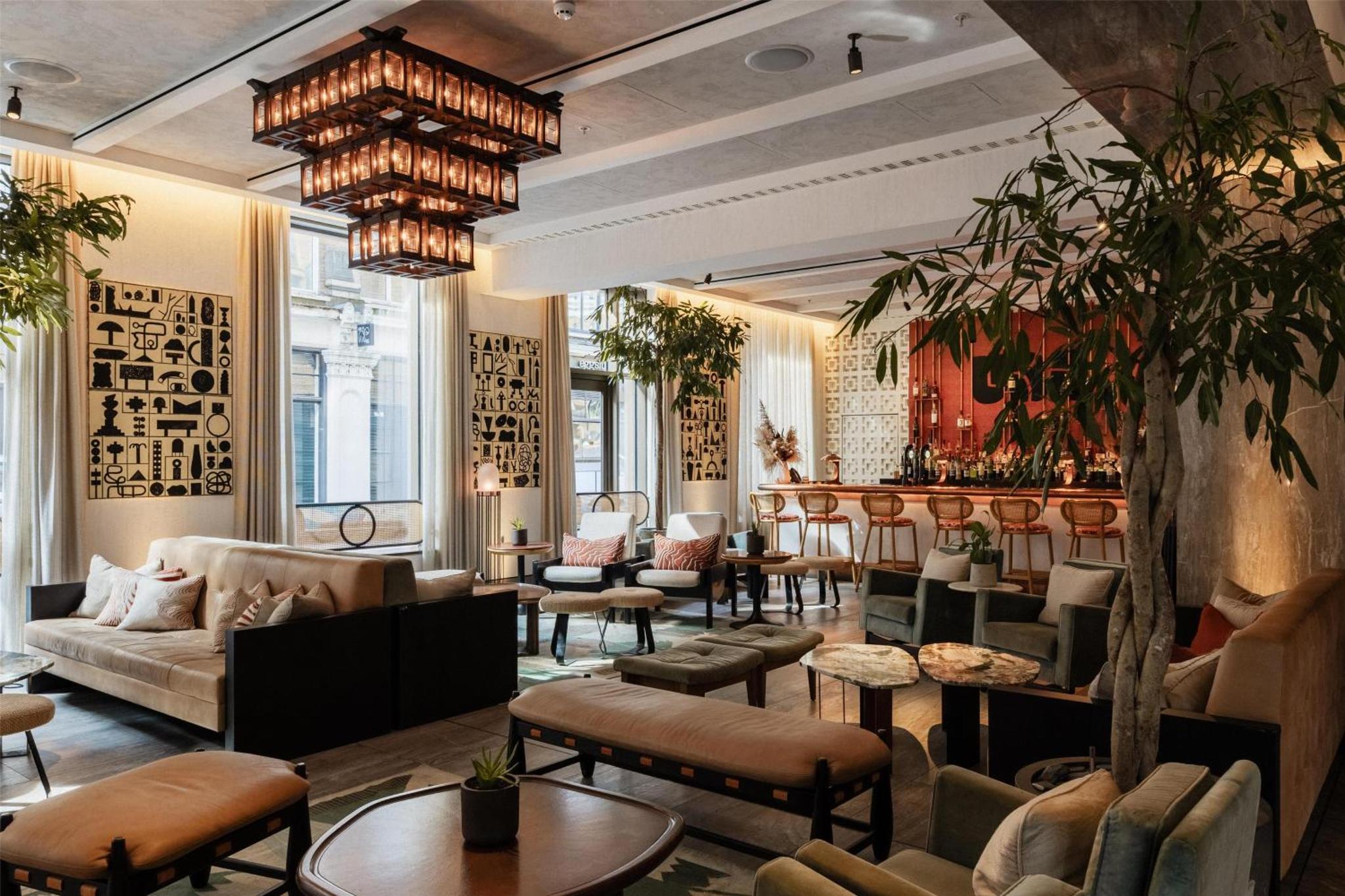 a lobby with couches and tables and a bar at Hart Shoreditch Hotel London, Curio Collection by Hilton in London