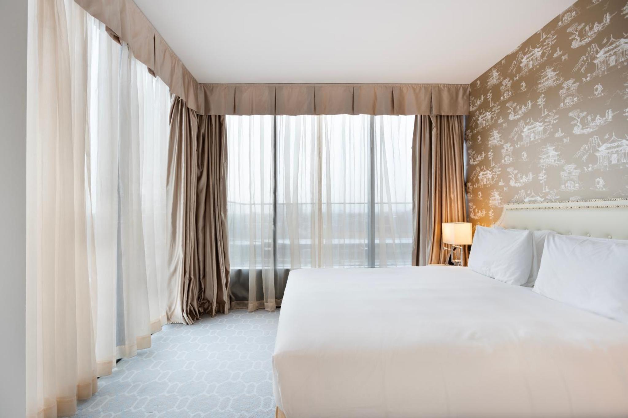 a bedroom with a white bed and a large window at Dorsett Shepherds Bush London in London