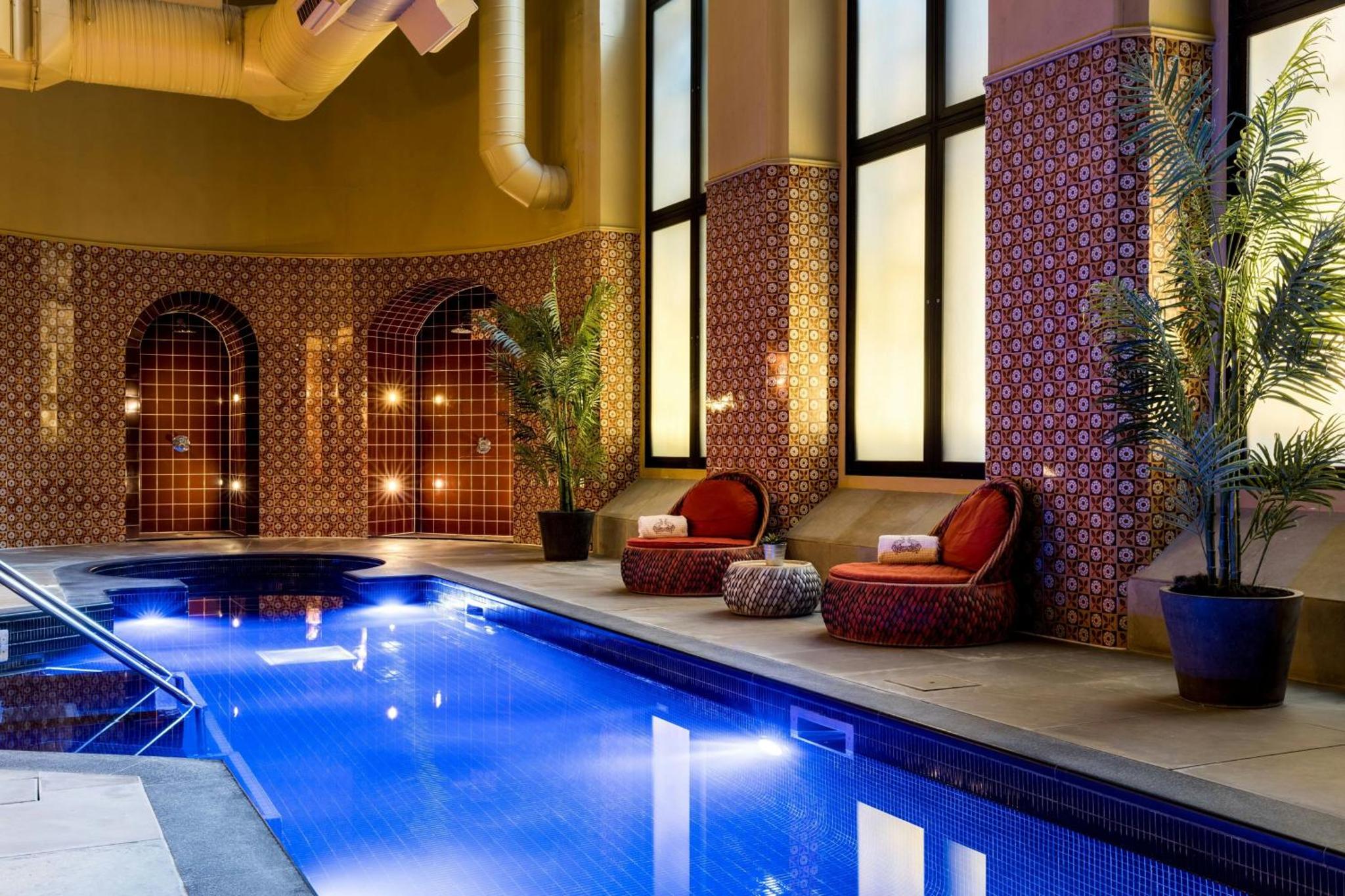 a swimming pool in a hotel with two chairs next to it at St Pancras London, Autograph Collection in London
