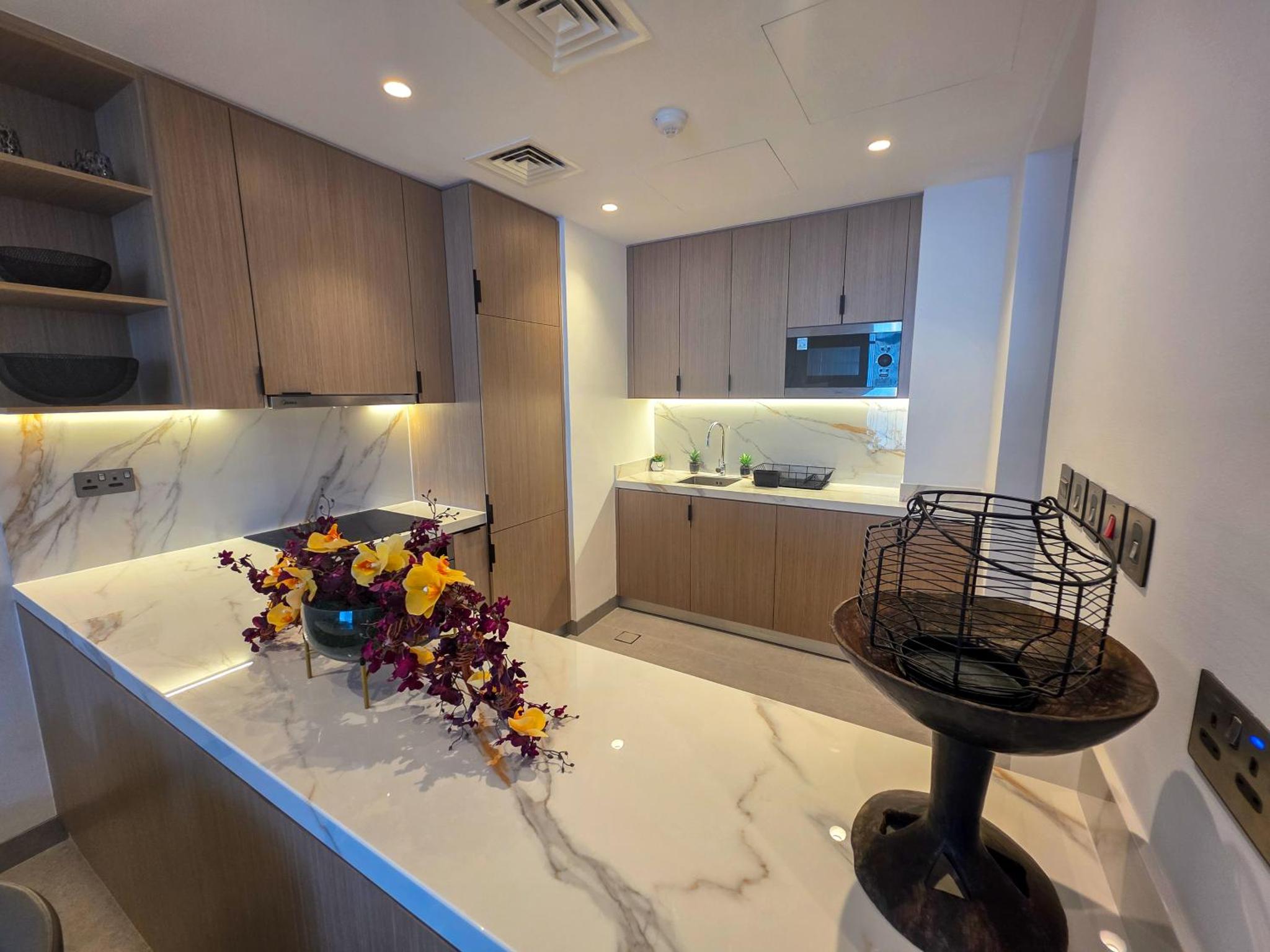 a kitchen with a counter top with flowers on it at Pearlhouse Bahrain Brand New 1BR with Balcony in Manama