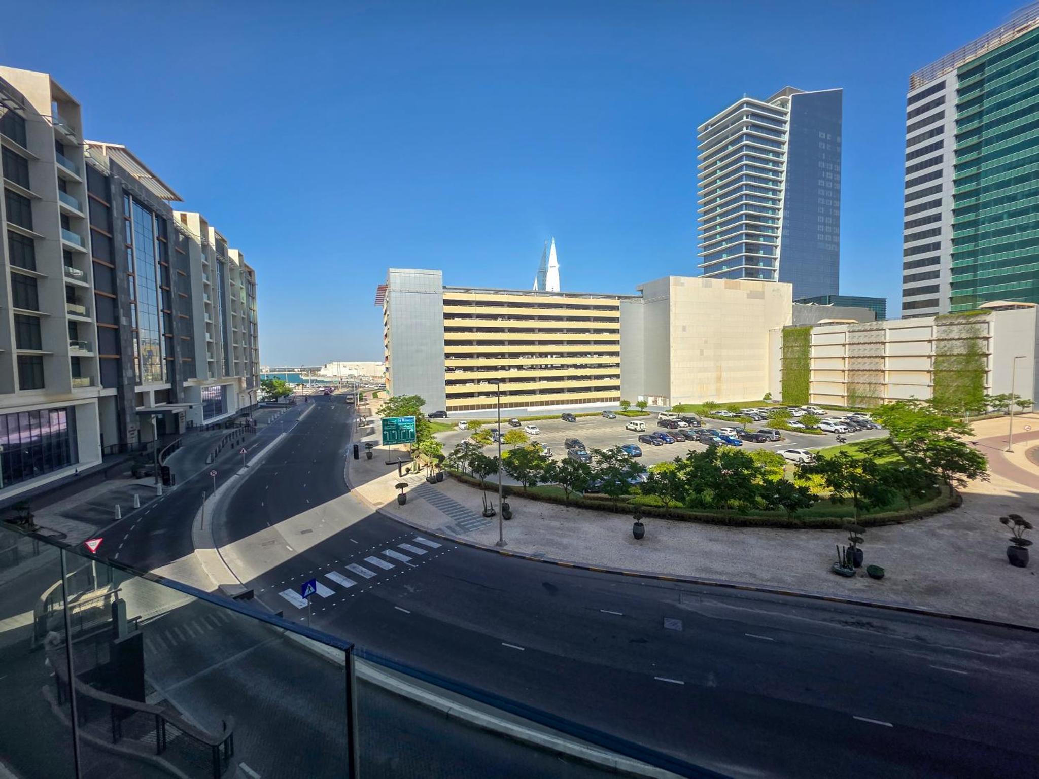 an empty street in a city with tall buildings at Pearlhouse Bahrain Brand New 1BR with Balcony in Manama