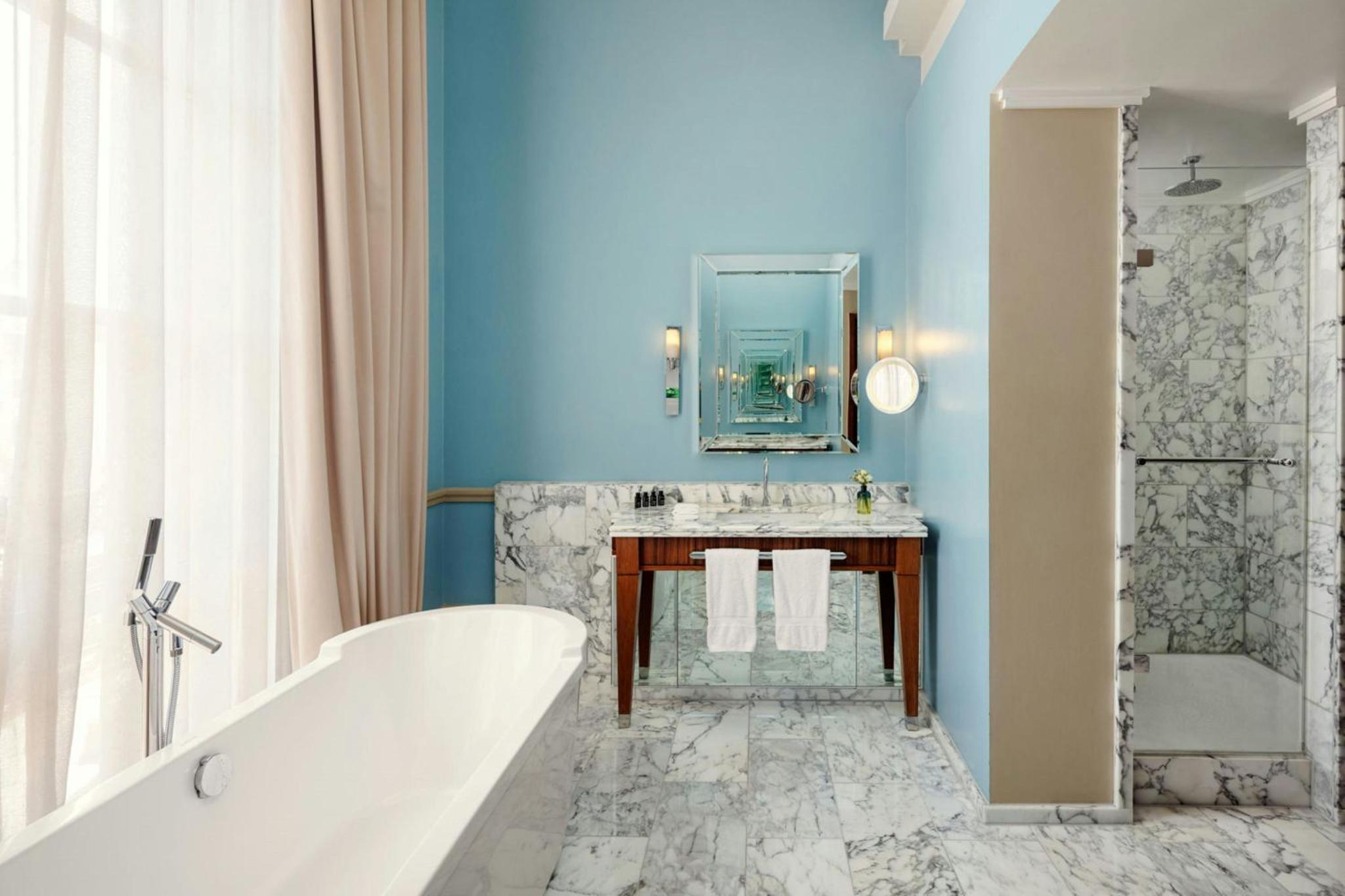 a bathroom with a tub and a sink and a mirror at St Pancras London, Autograph Collection in London