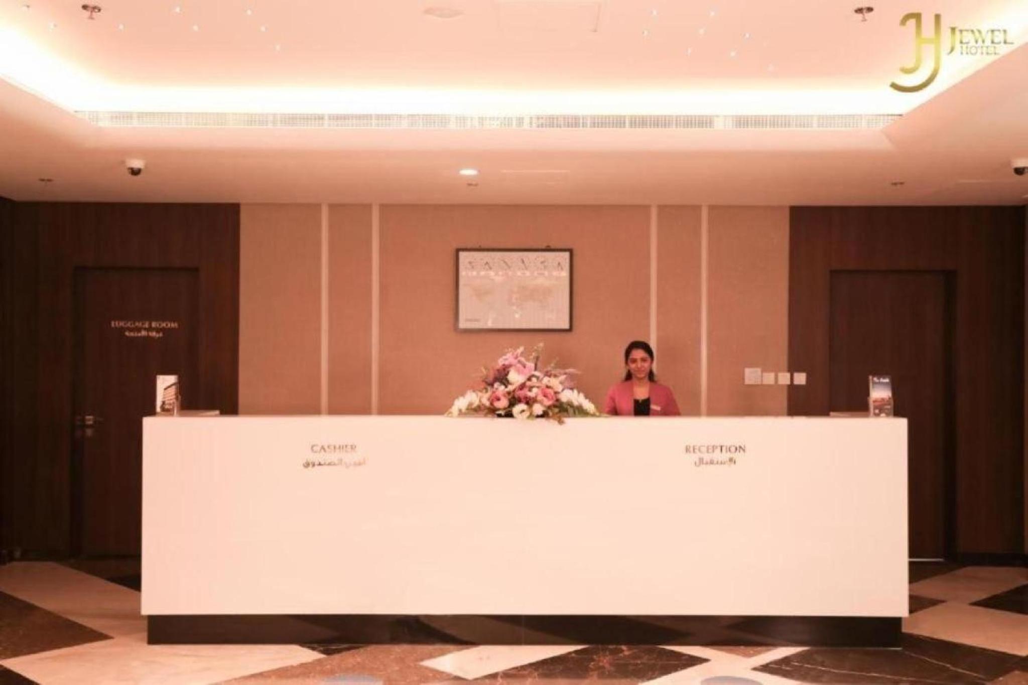 a woman standing behind a counter in a hotel lobby at Bellvila Luxury Downtown Adliya Formerly Jewel Hotel in Manama +46 photos