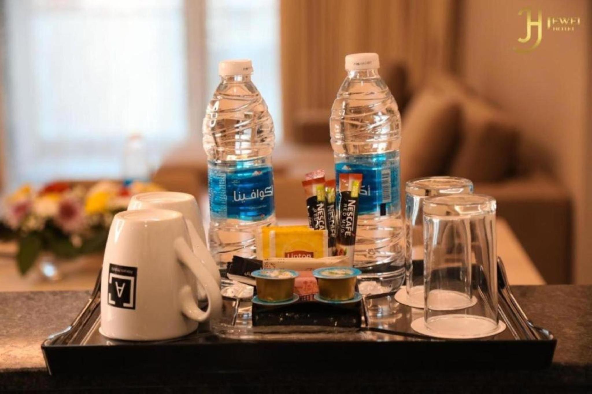a tray with bottles of water and other items on a table at Bellvila Luxury Downtown Adliya Formerly Jewel Hotel in Manama