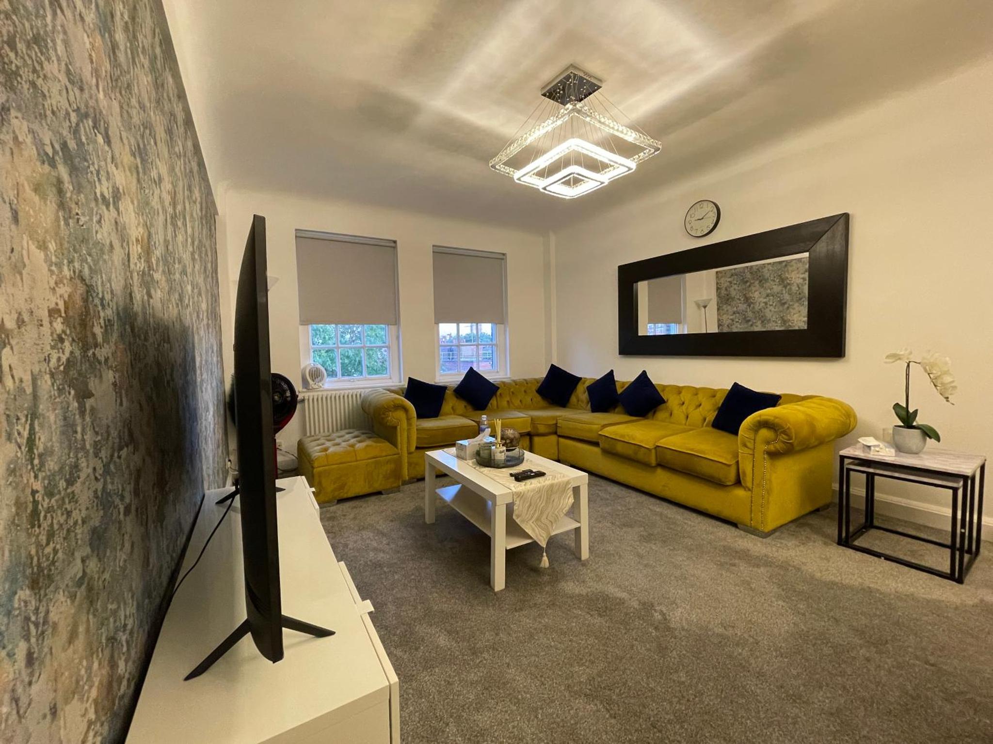 a living room with a yellow couch and a table at Kensington Apartment in London