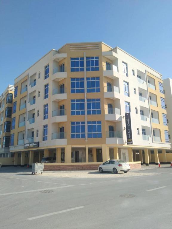a large building with a car parked in front of it at Marine Beach Apartment in Seef