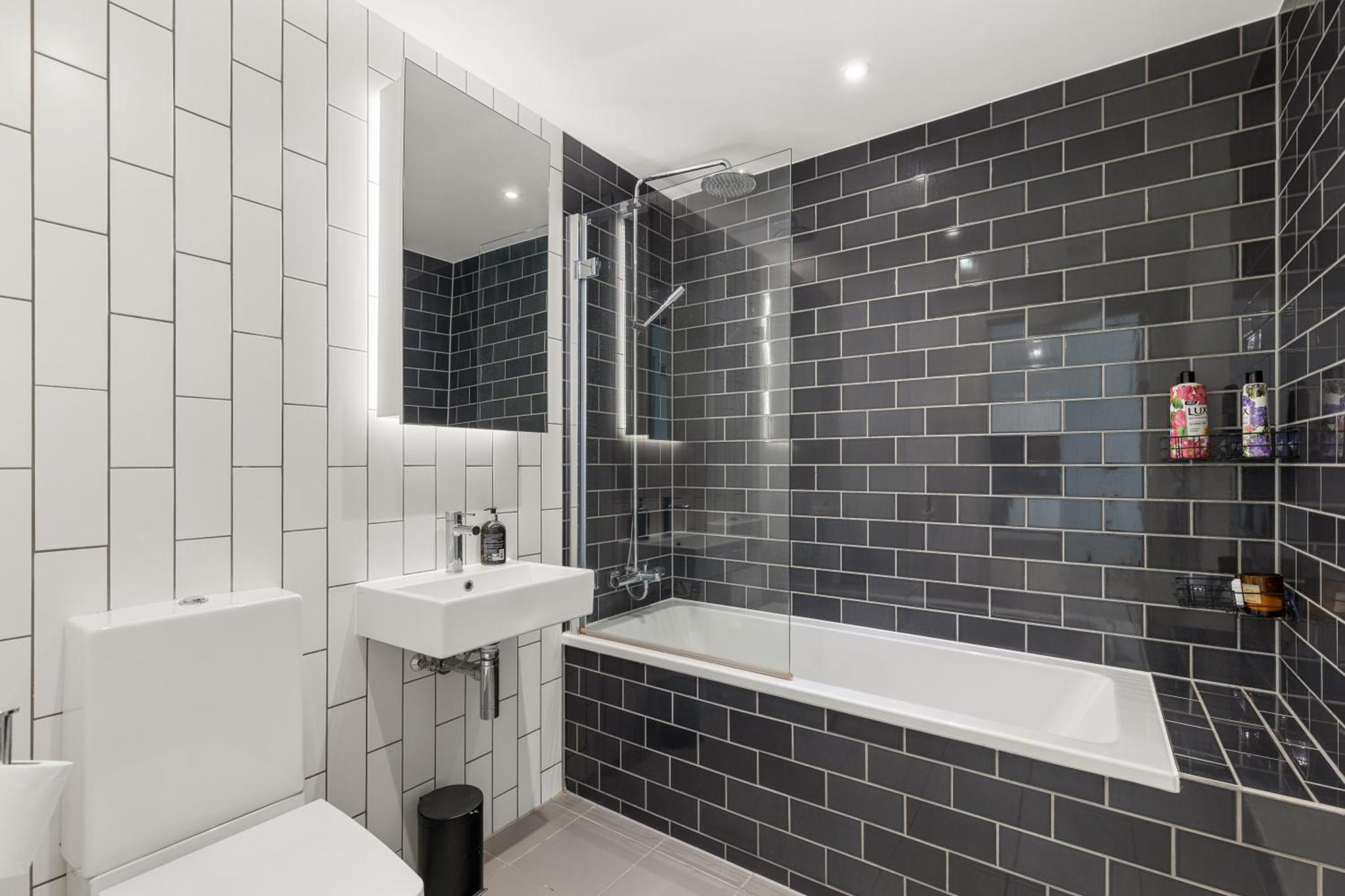 a black and white bathroom with a sink and a bath tub at Spacious modern 1 bed Apartment. in London +13 photos
