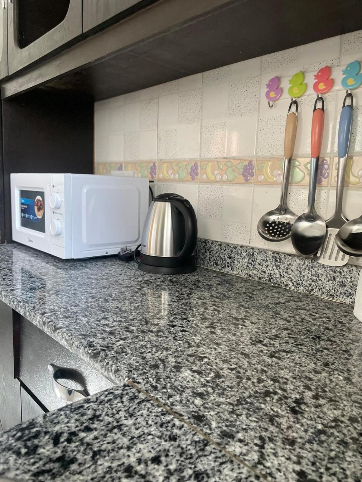 a kitchen counter with a white microwave and utensils at Spacious 2 bedroom apartment in Jazīrat Umm ash Shajar
