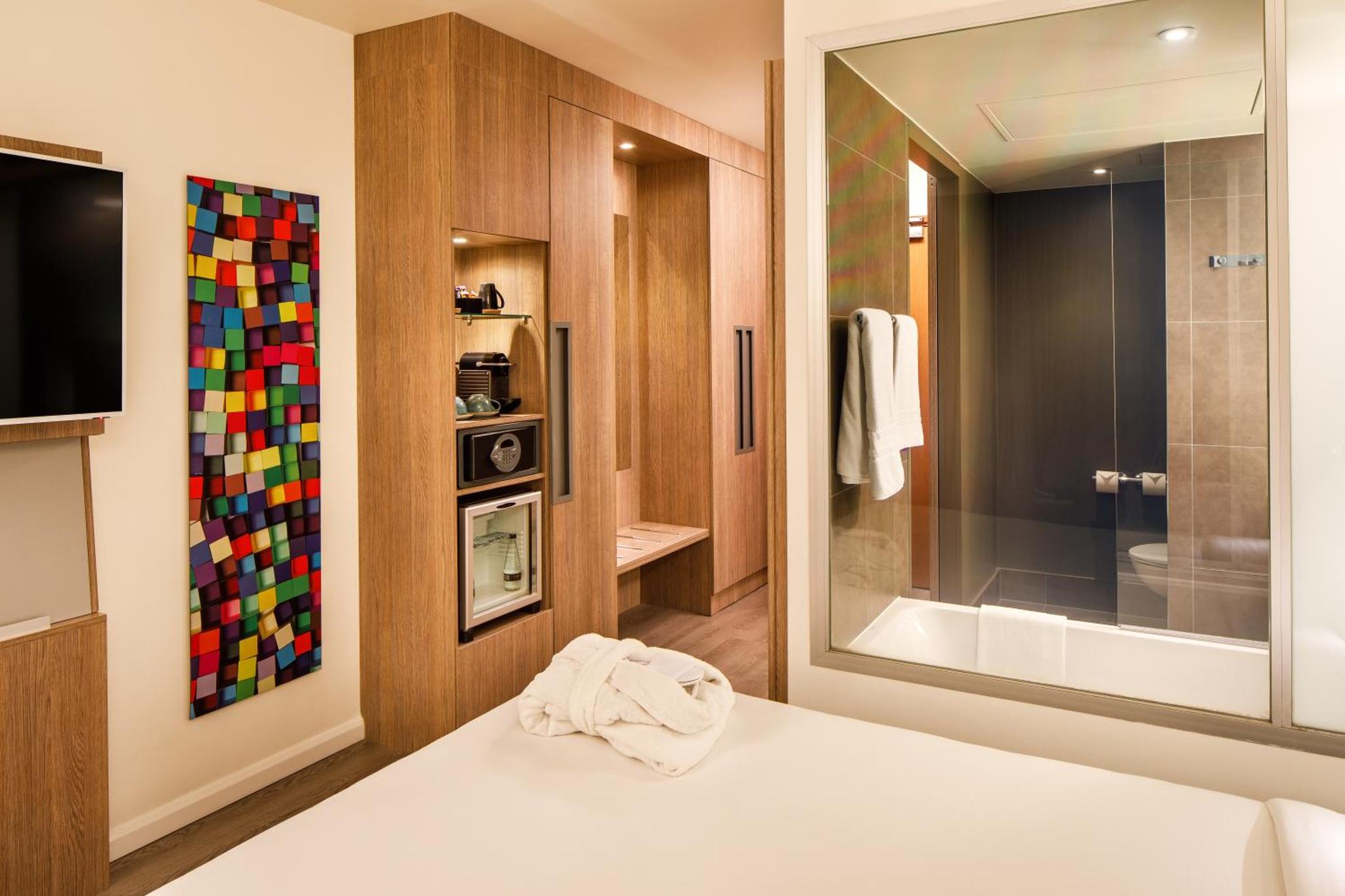 a bathroom with a bed with a mirror and a television at Novotel London Bridge in London