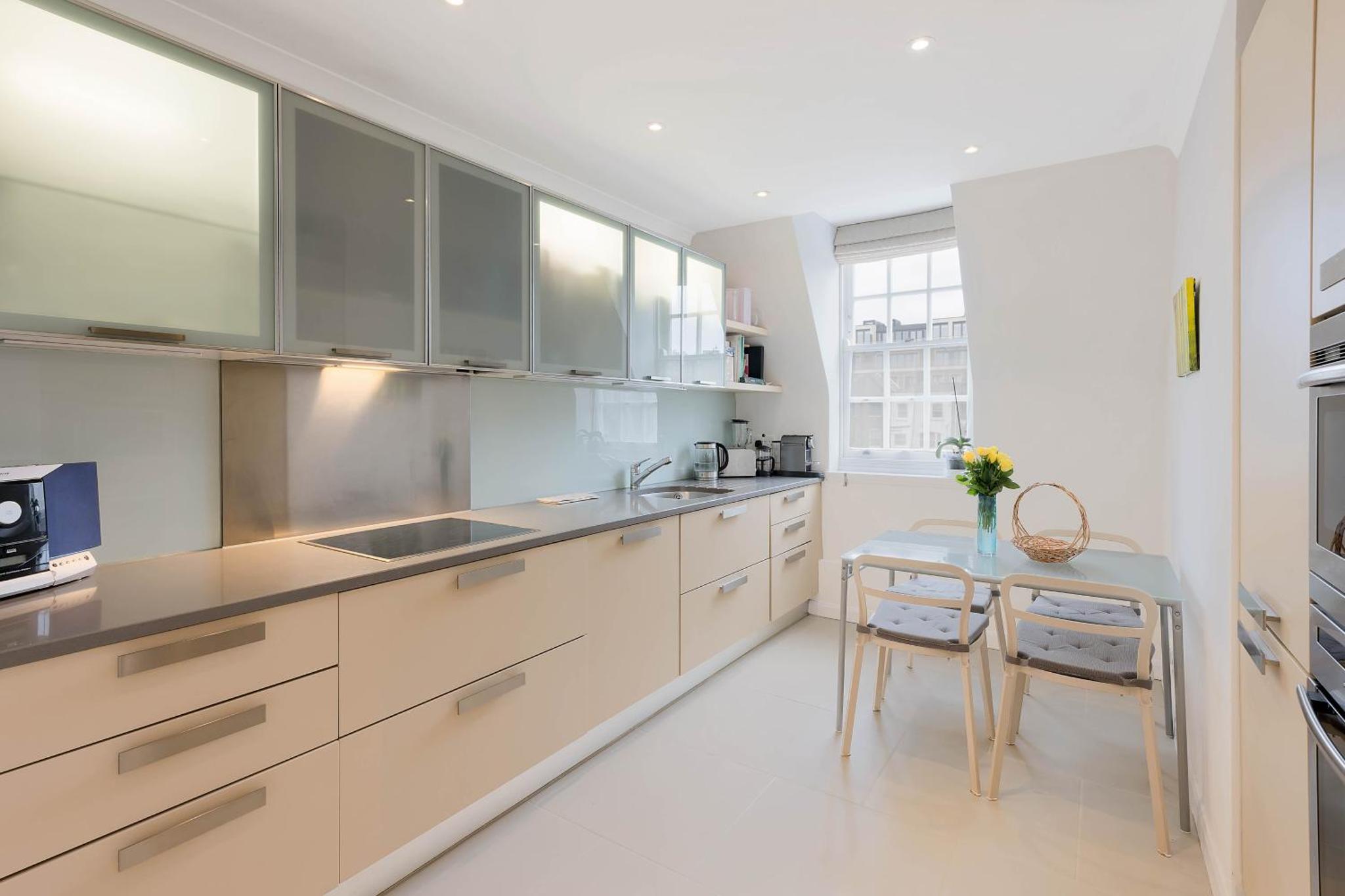 a kitchen with white cabinets and a table and a sink at Top view Notting Hill Kensington in London