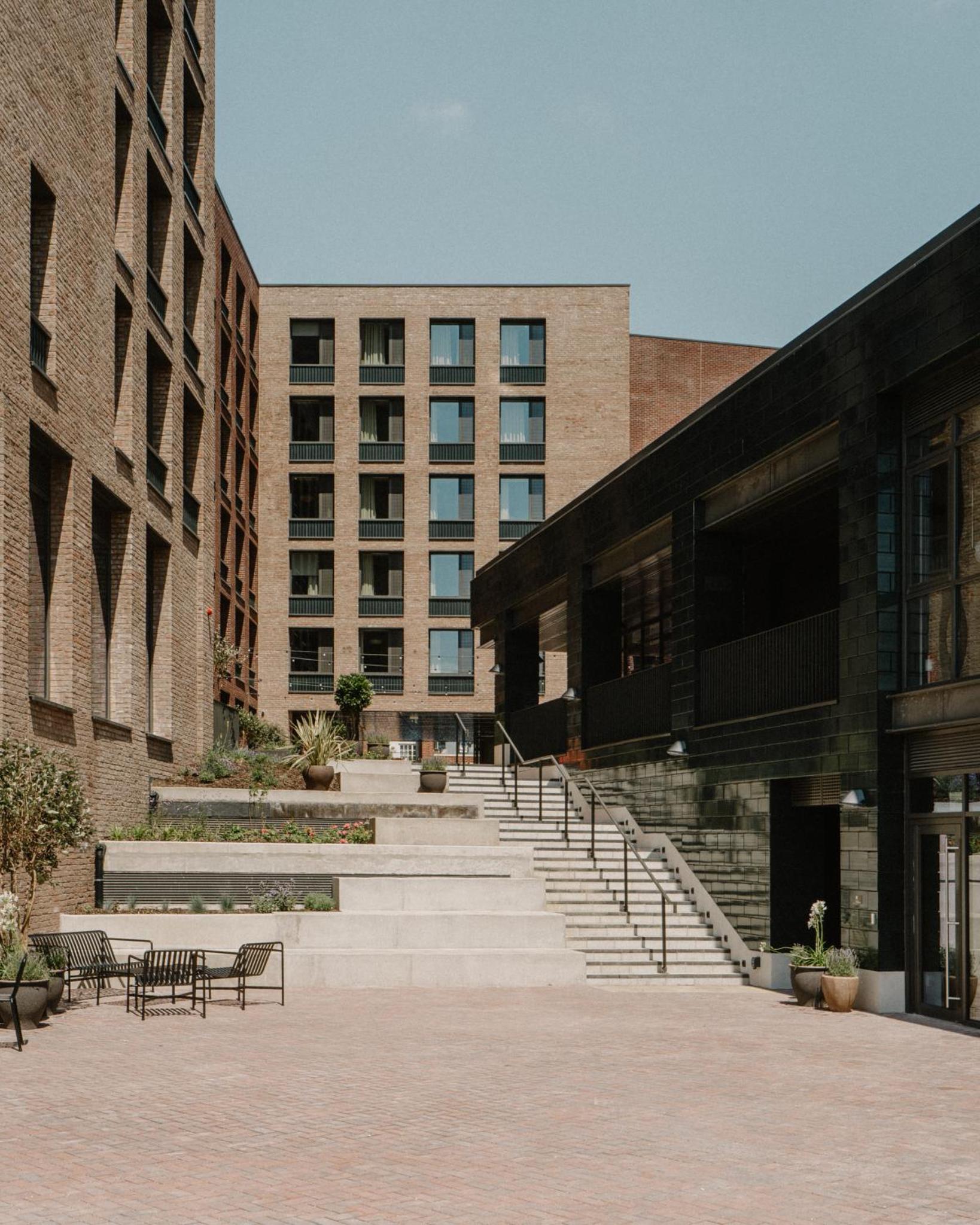 a group of buildings with stairs and tables and benches at Mason & Fifth, Westbourne Park in London