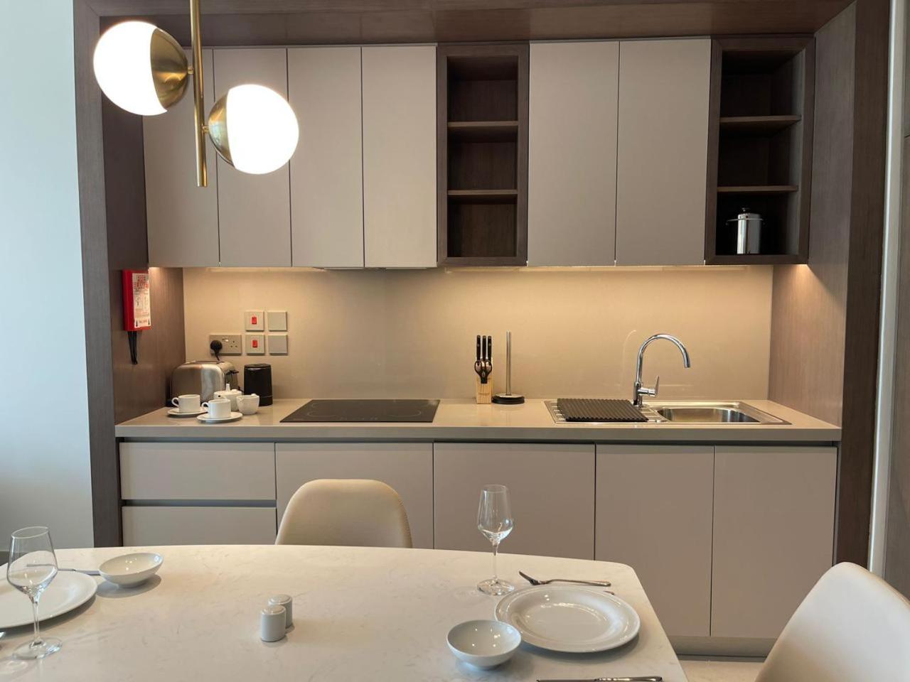 a kitchen with white cabinets and a table with wine glasses at Address Residences Beach Resort Bahrain in Rayyā