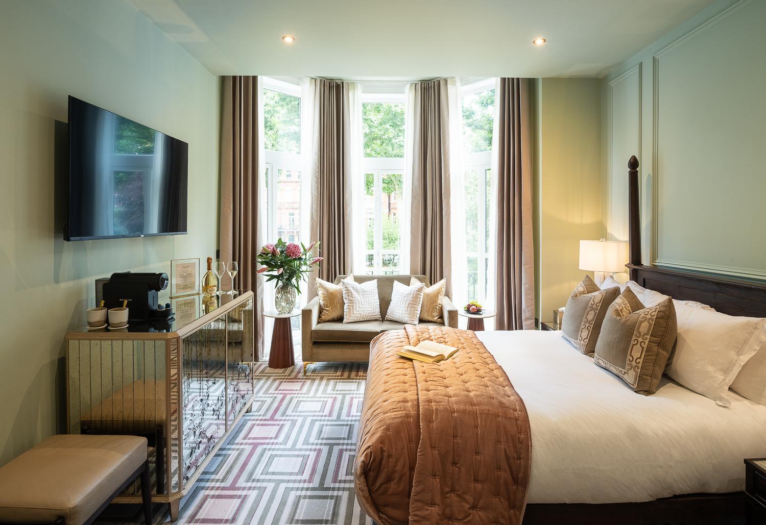 a bedroom with a large bed and a living room at Ellen Kensington in London