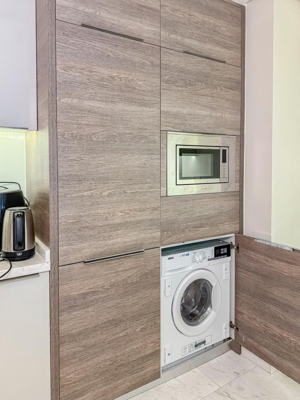 a kitchen with a washing machine and a microwave at 2 Bedroom Apartment in Bahrain Bay with a four season view in Manama