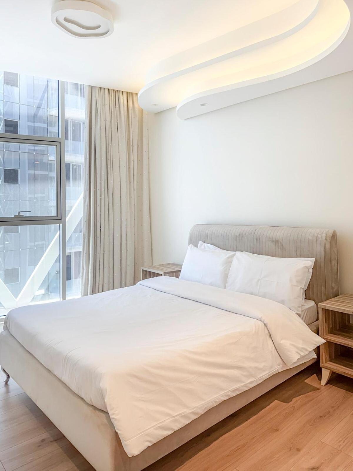 a white bedroom with a bed and a window at 2 Bedroom Apartment in Bahrain Bay with a four season view in Manama +51 photos