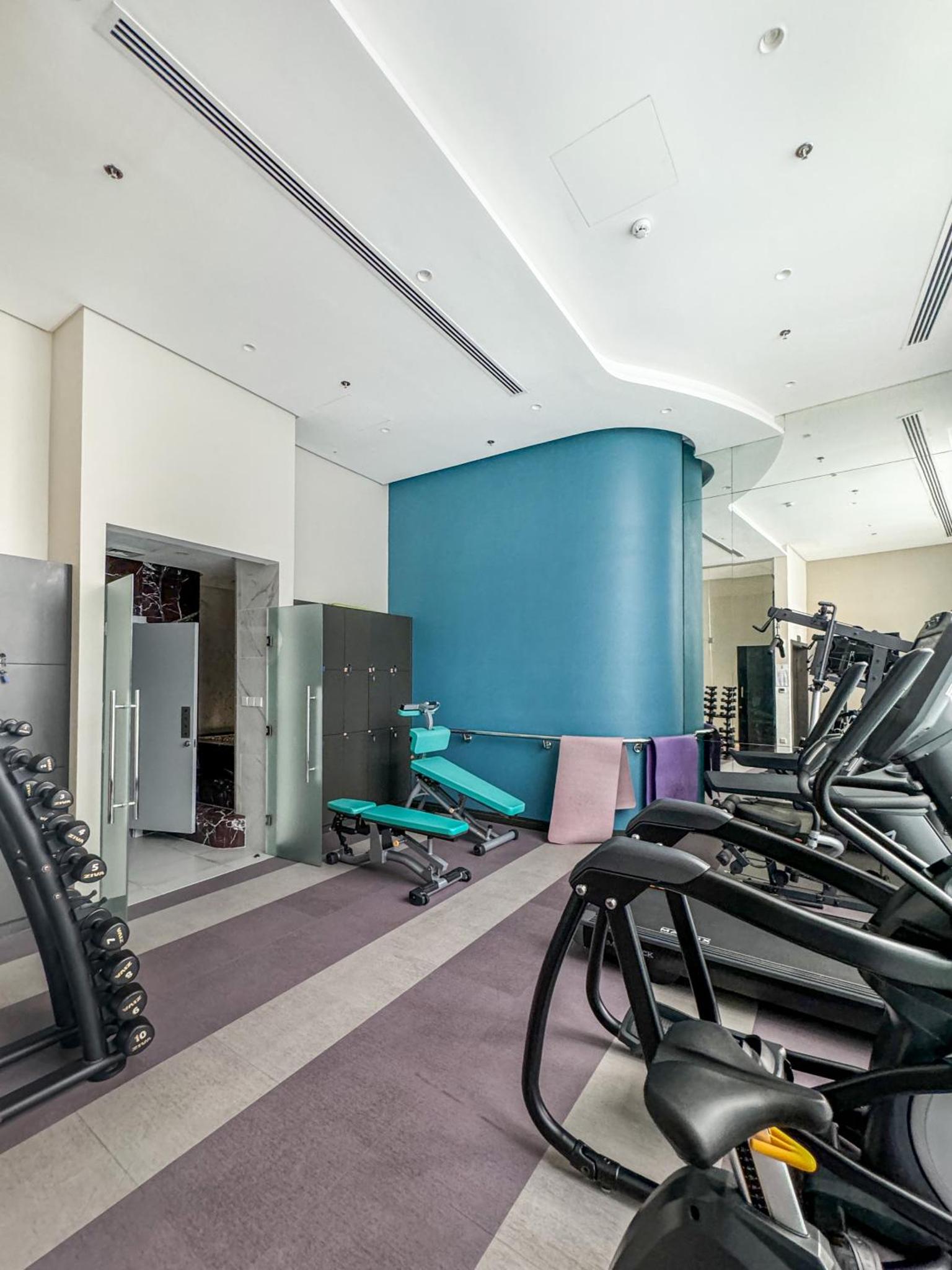 a gym with treadmills and cardio equipment at Luxurious 2BR APT in Bahrain Bay in Manama