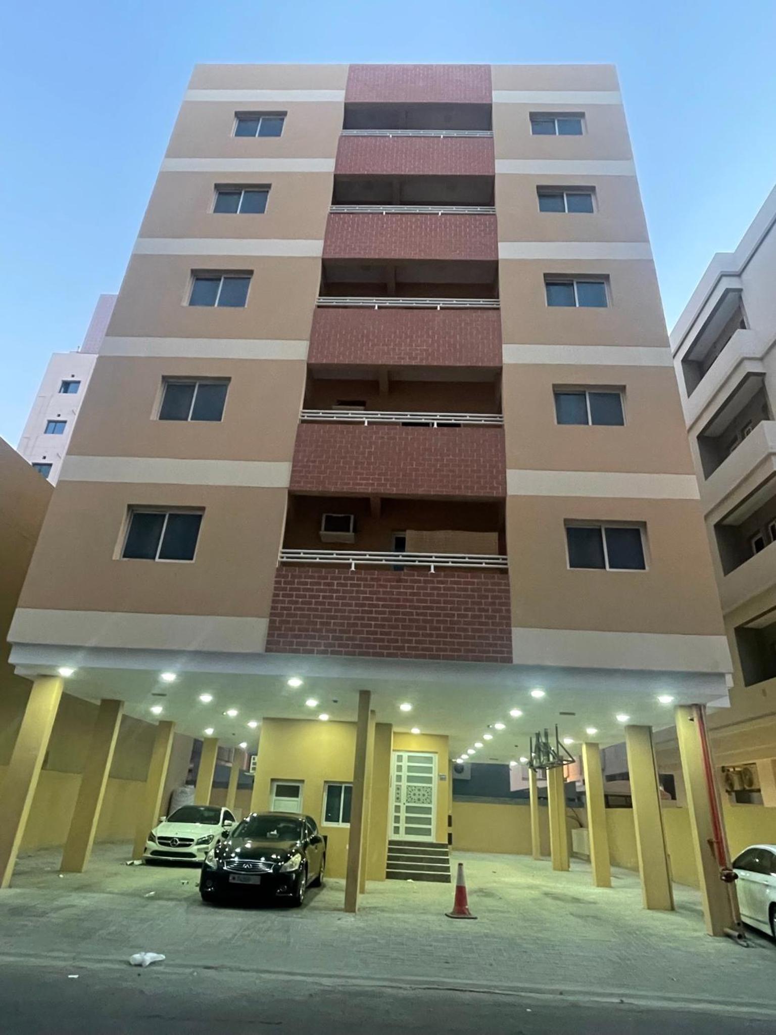 a building with cars parked in front of it at Spacious 2 bedroom apartment in Jazīrat Umm ash Shajar
