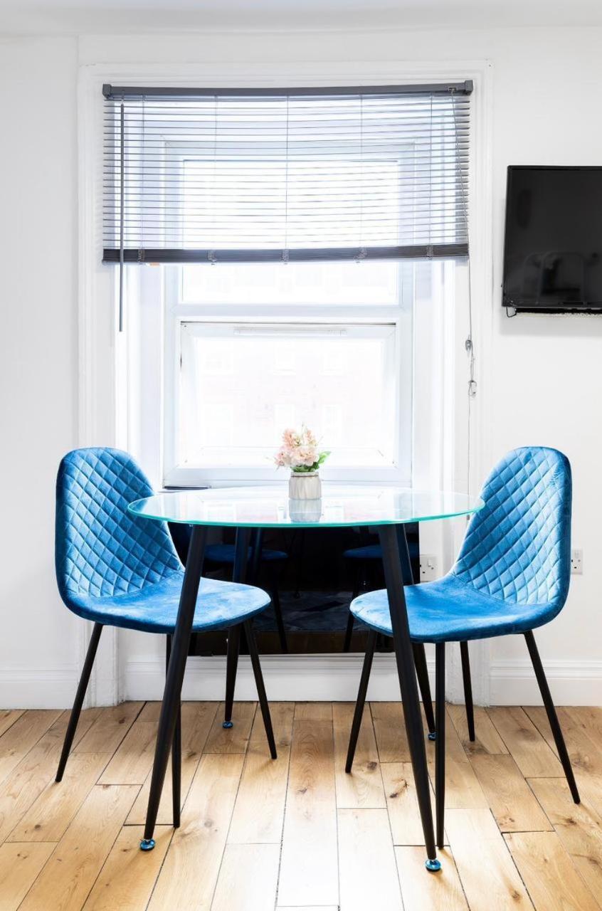 a dining room table with two blue chairs and a window at Hyde Park Budget Studios! in London