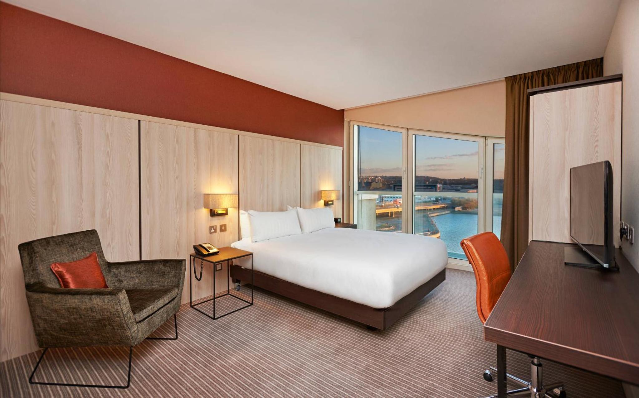 a hotel room with a bed and a chair and a television at DoubleTree By Hilton London Excel in London