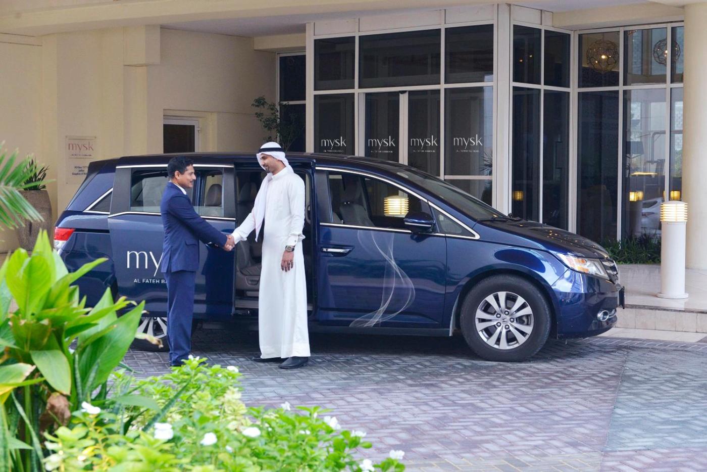 a man shaking hands with a man in front of a car at Mysk Al Fateh Bahrain in Manama