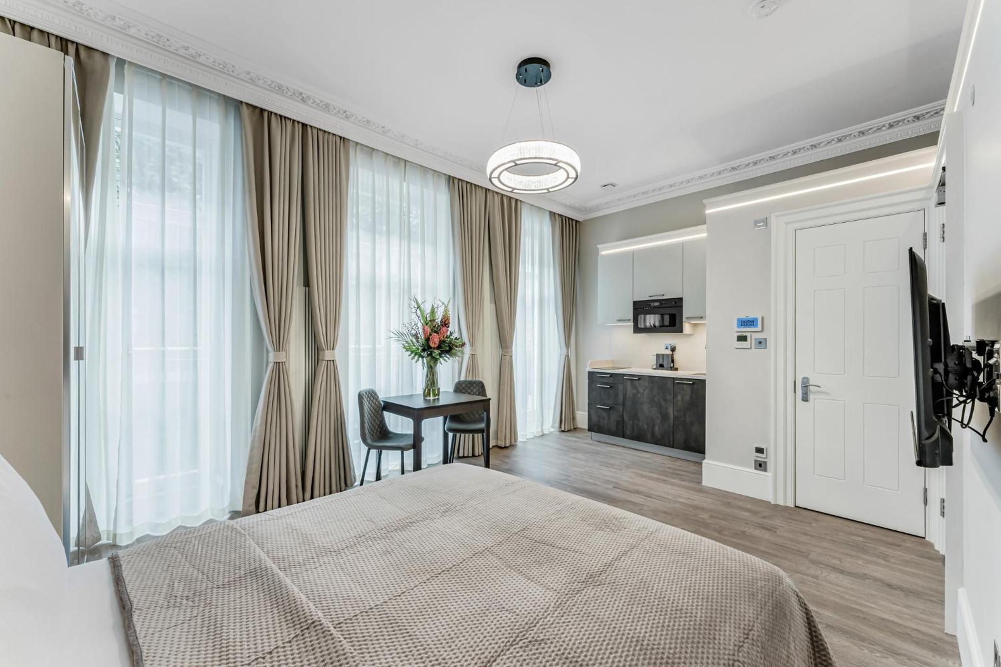 a bedroom with a bed and a table with a vase of flowers at Cleveland Residences Bloomsbury in London