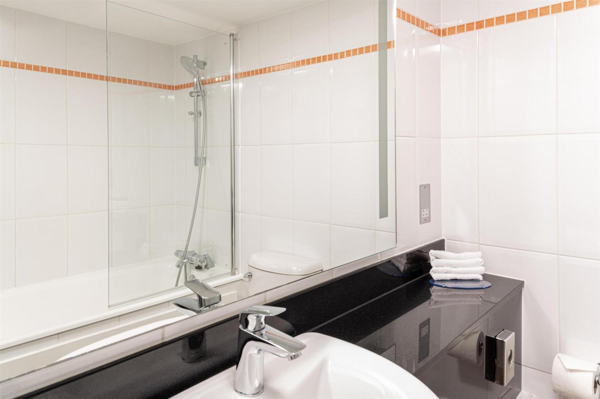 a bathroom with a sink and a mirror at Hilton London Kensington Hotel in London
