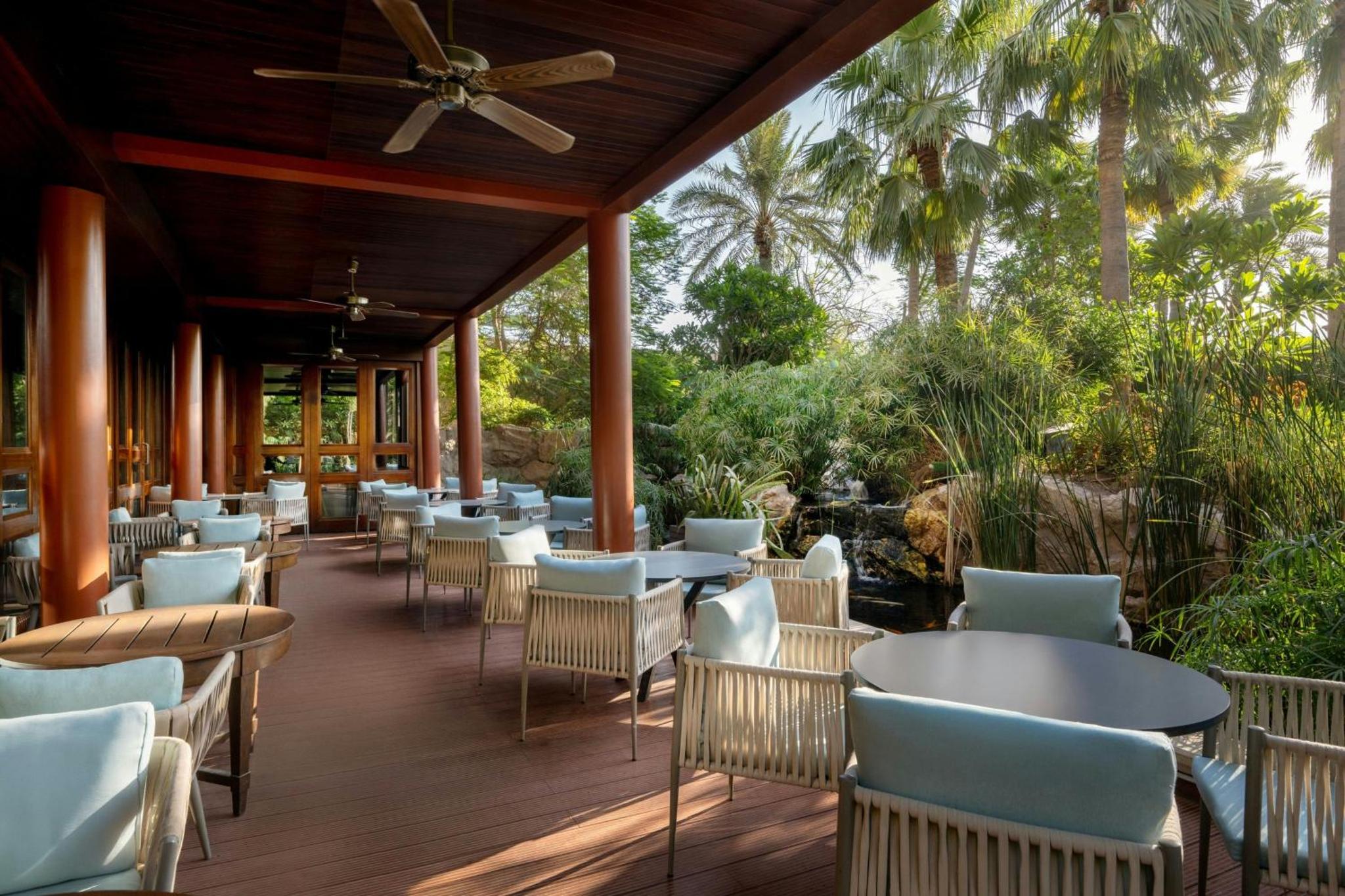a restaurant with tables and chairs on a wooden deck at Gulf Hotel Bahrain Convention and SPA in Manama