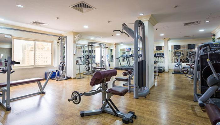 a gym with several treadms and machines in a room at Al Safir Hotel in Manama