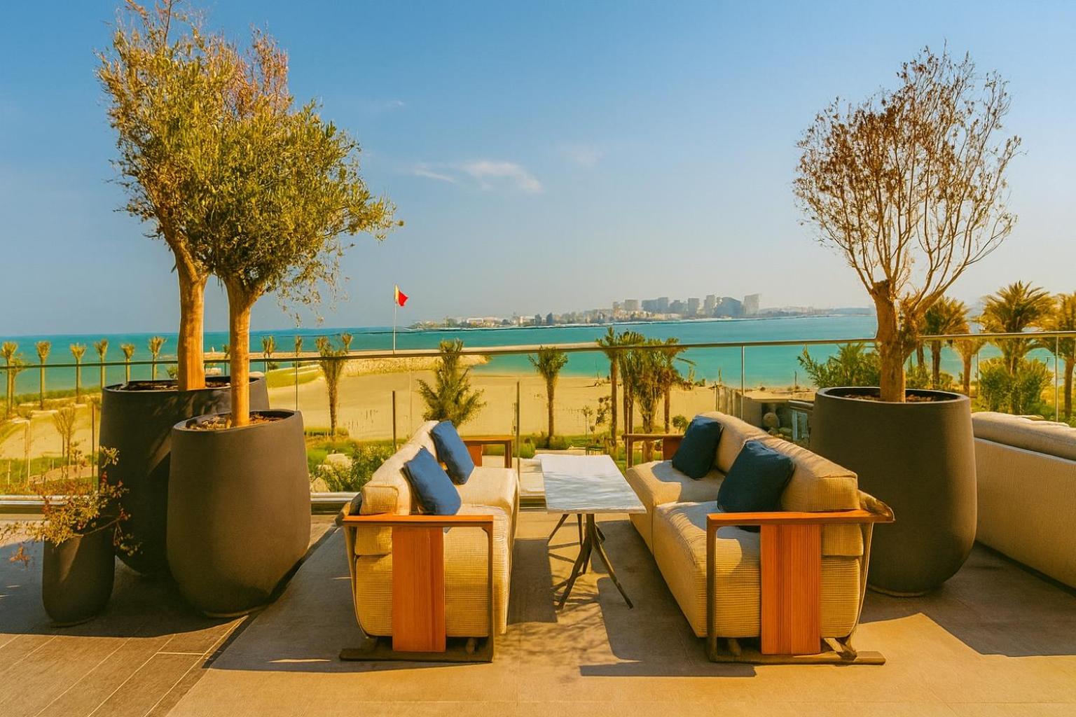 a patio with couches and a table with a view of the beach at Address Residence Marassi Vista-studio in Amwaj Island