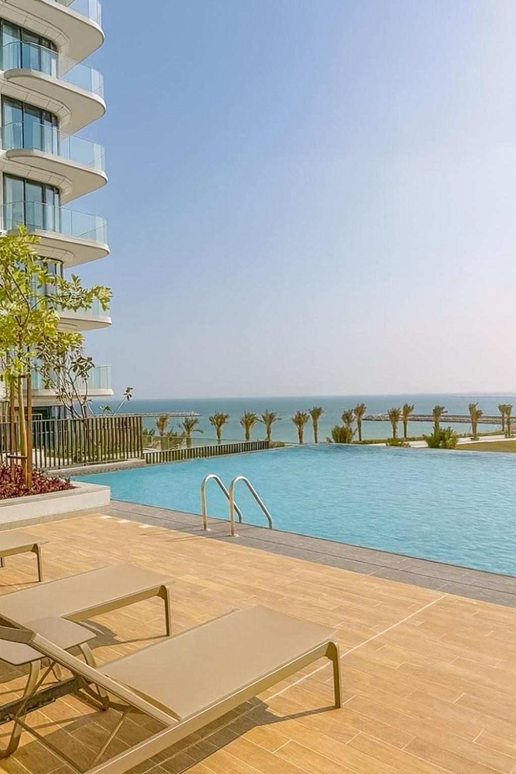 a swimming pool with a chair next to a building at Address Residence Marassi Vista-studio in Amwaj Island