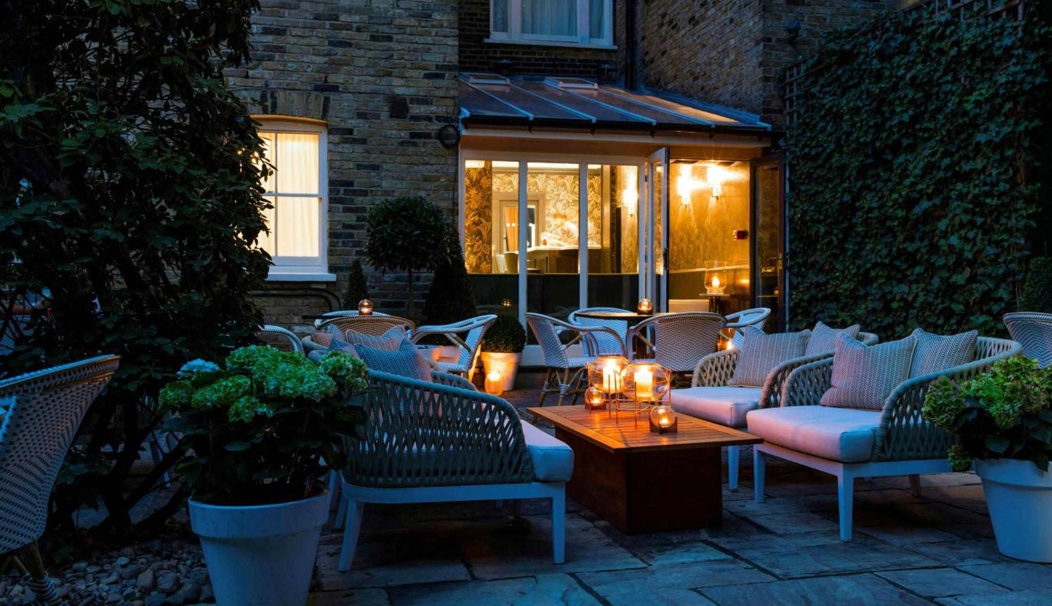 a patio with chairs and a table with candles at The Academy - Small Luxury Hotels of the World in London