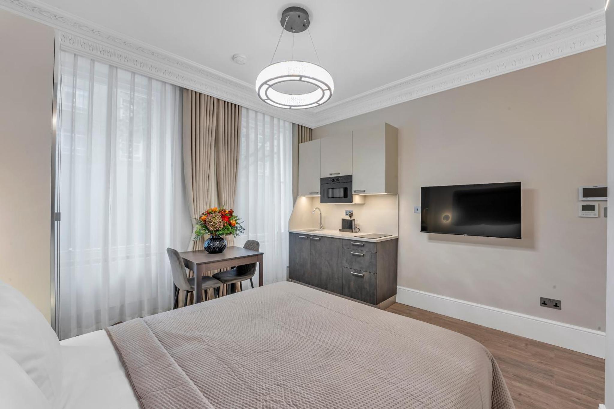a bedroom with a bed and a desk and a television at Cleveland Residences Bloomsbury in London