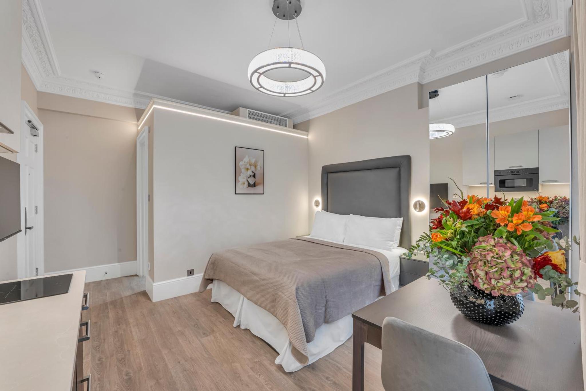 a hotel room with a bed and a table with flowers at Cleveland Residences Bloomsbury in London