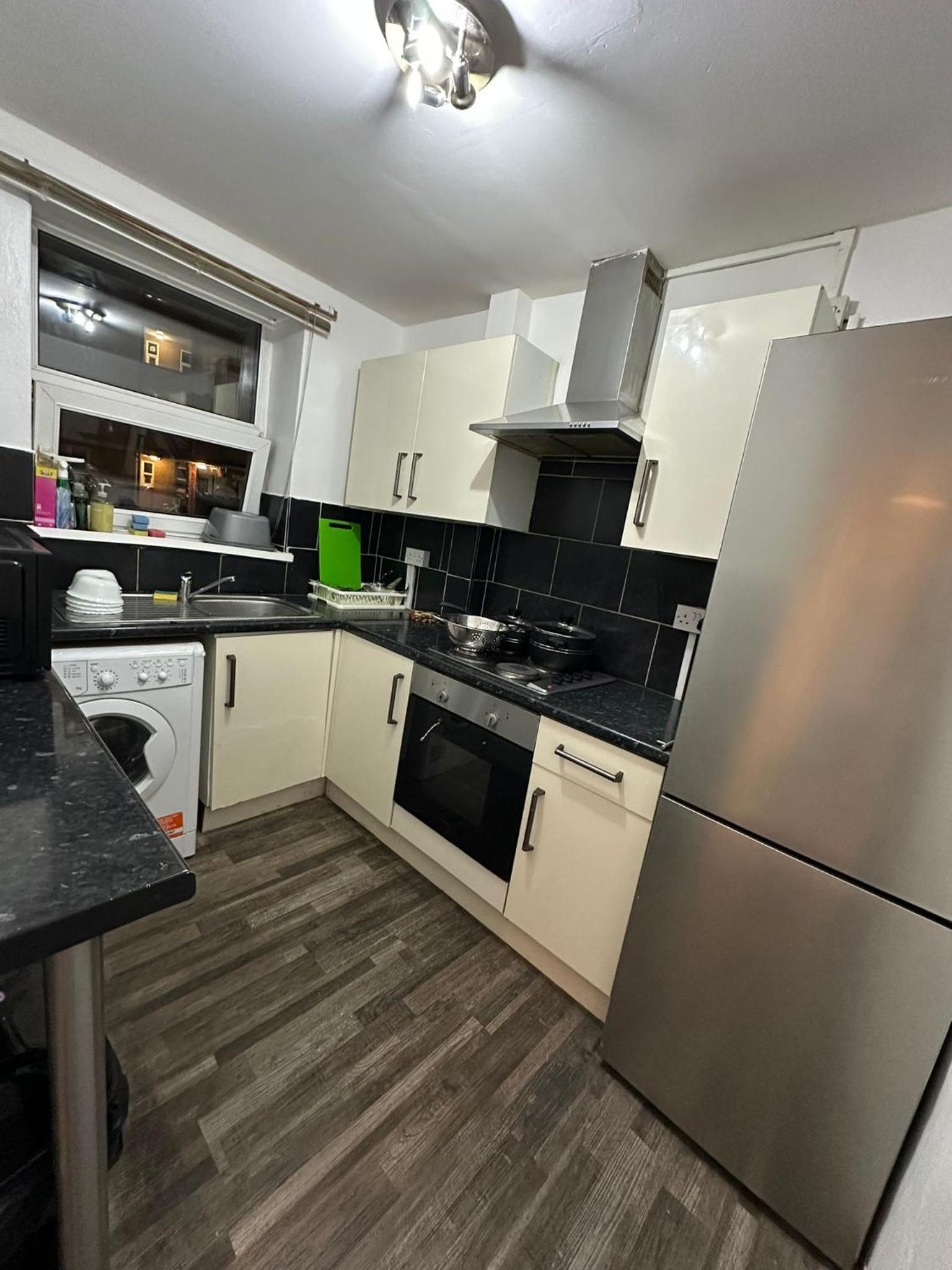 a kitchen with white cabinets and a stainless steel refrigerator at Budget Ensuit Room, Quiet Stay, East London, Fast WiFi, Steps Away From London Eye, Near Metro in London