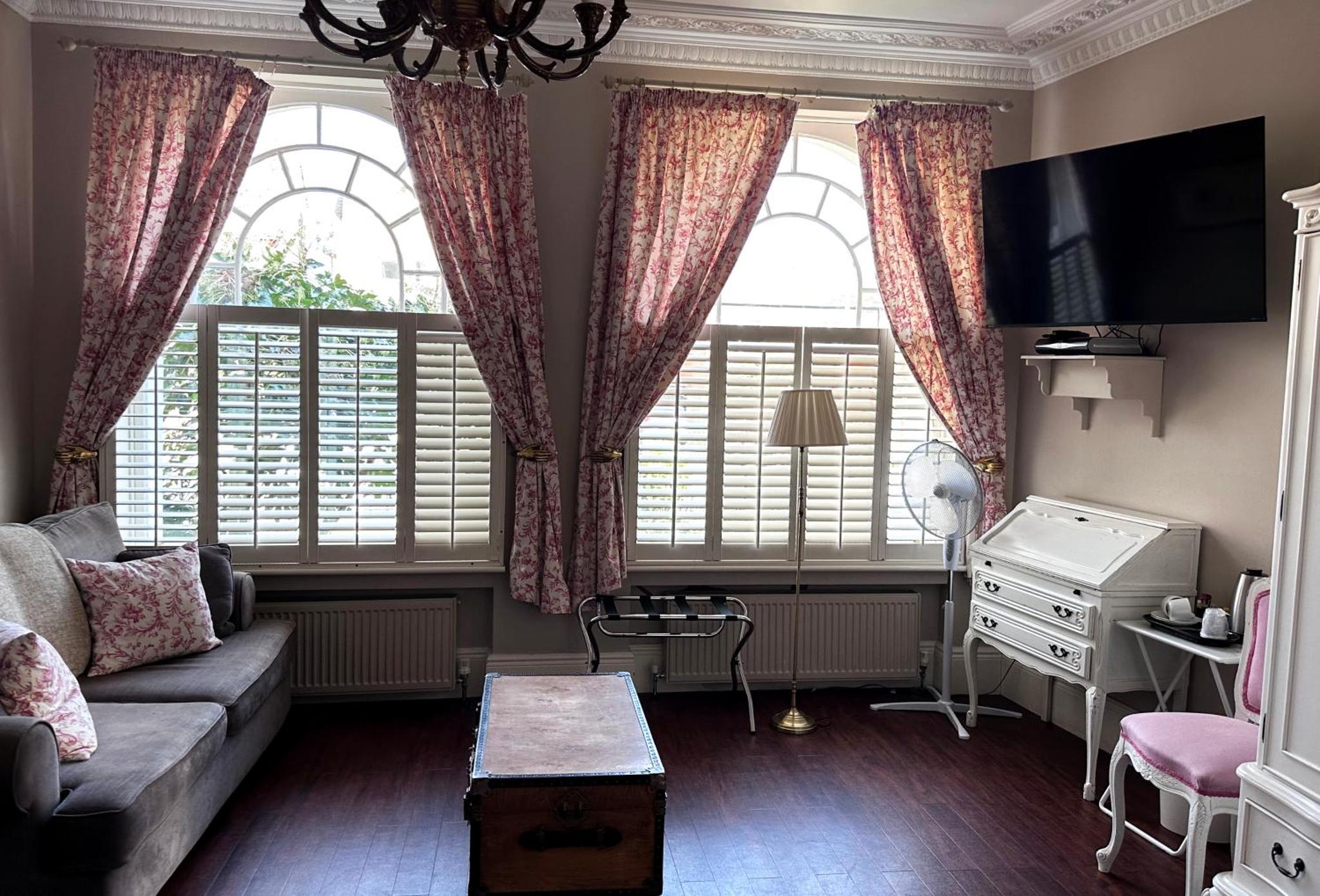 a living room with a couch and two large windows at Balham Lodge in London