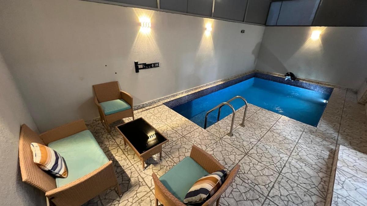 a pool in a room with two chairs and a table at Beachside villa with a pool! in Karzakkān