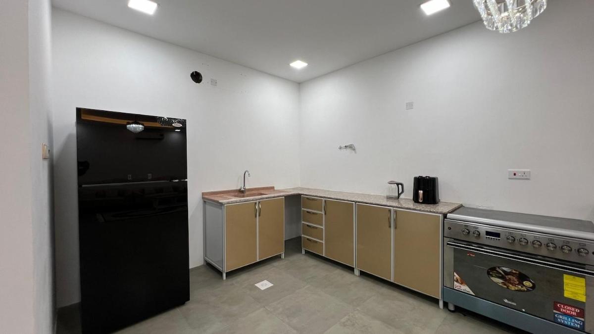 a kitchen with a black refrigerator and a stove at Beachside villa with a pool! in Karzakkān