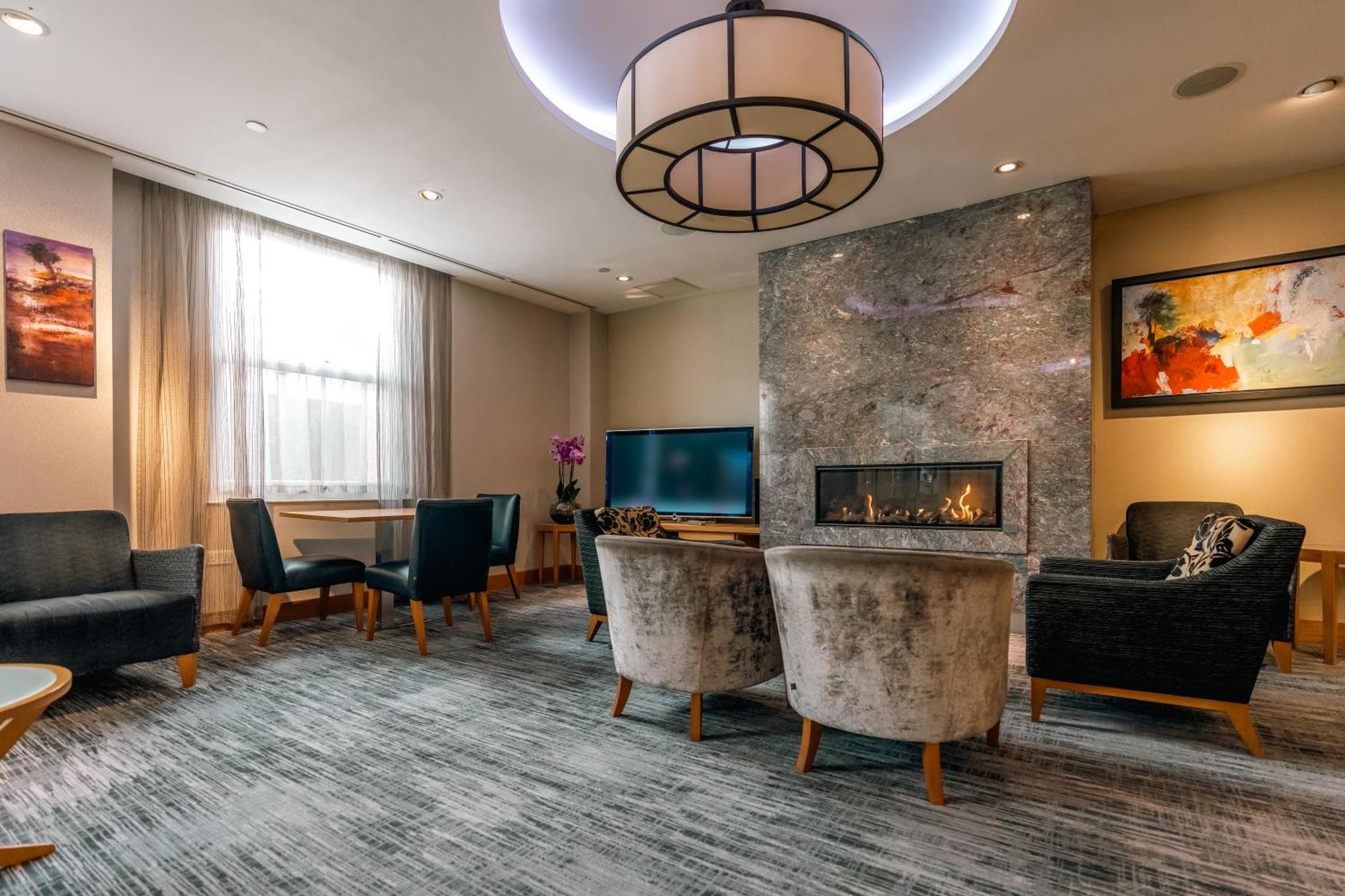 a lobby with a fireplace and a table and chairs at Club Quarters Hotel Covent Garden Holborn, London in London