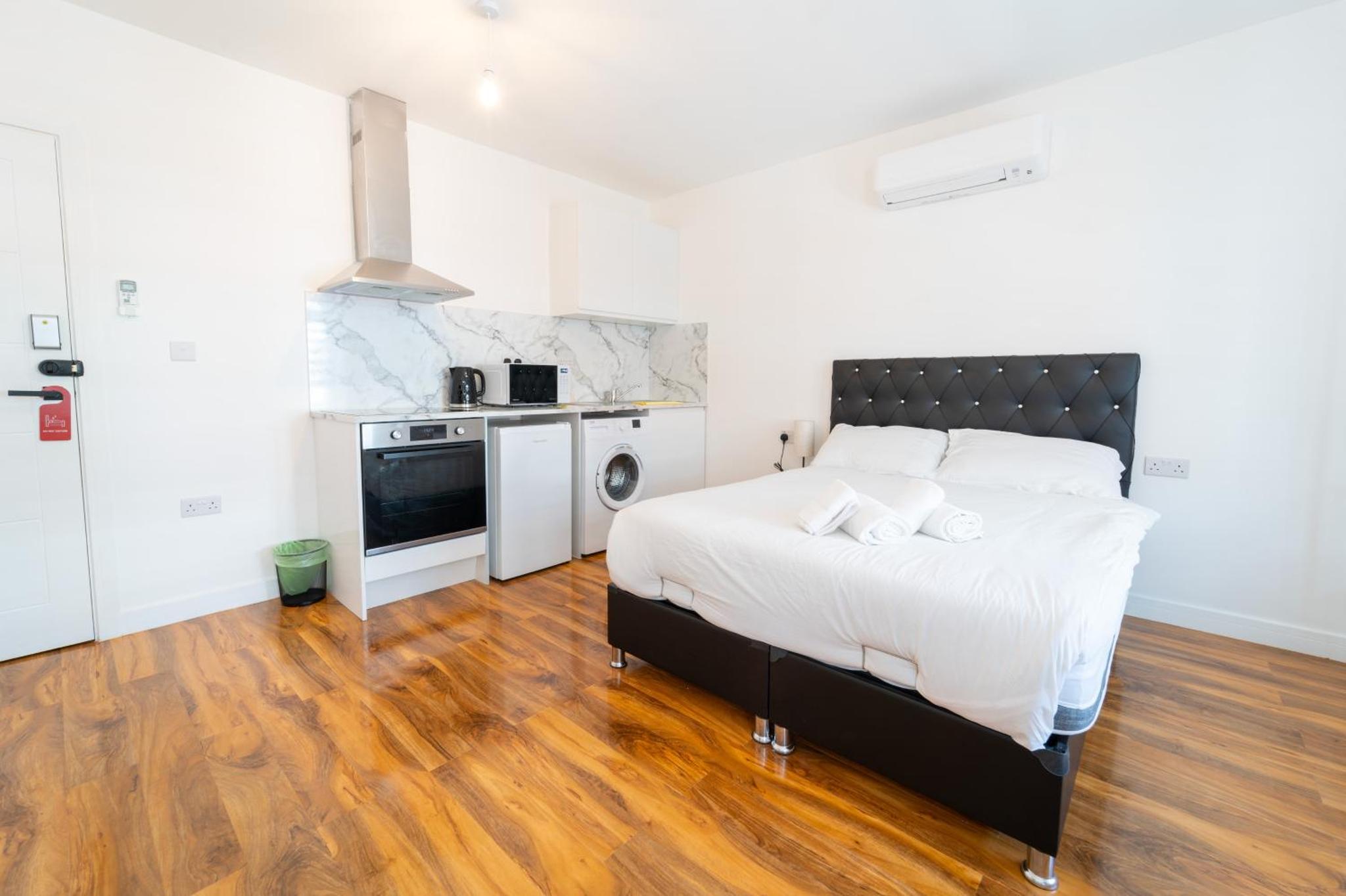a bedroom with a large bed and a kitchen at Centra High Road in London