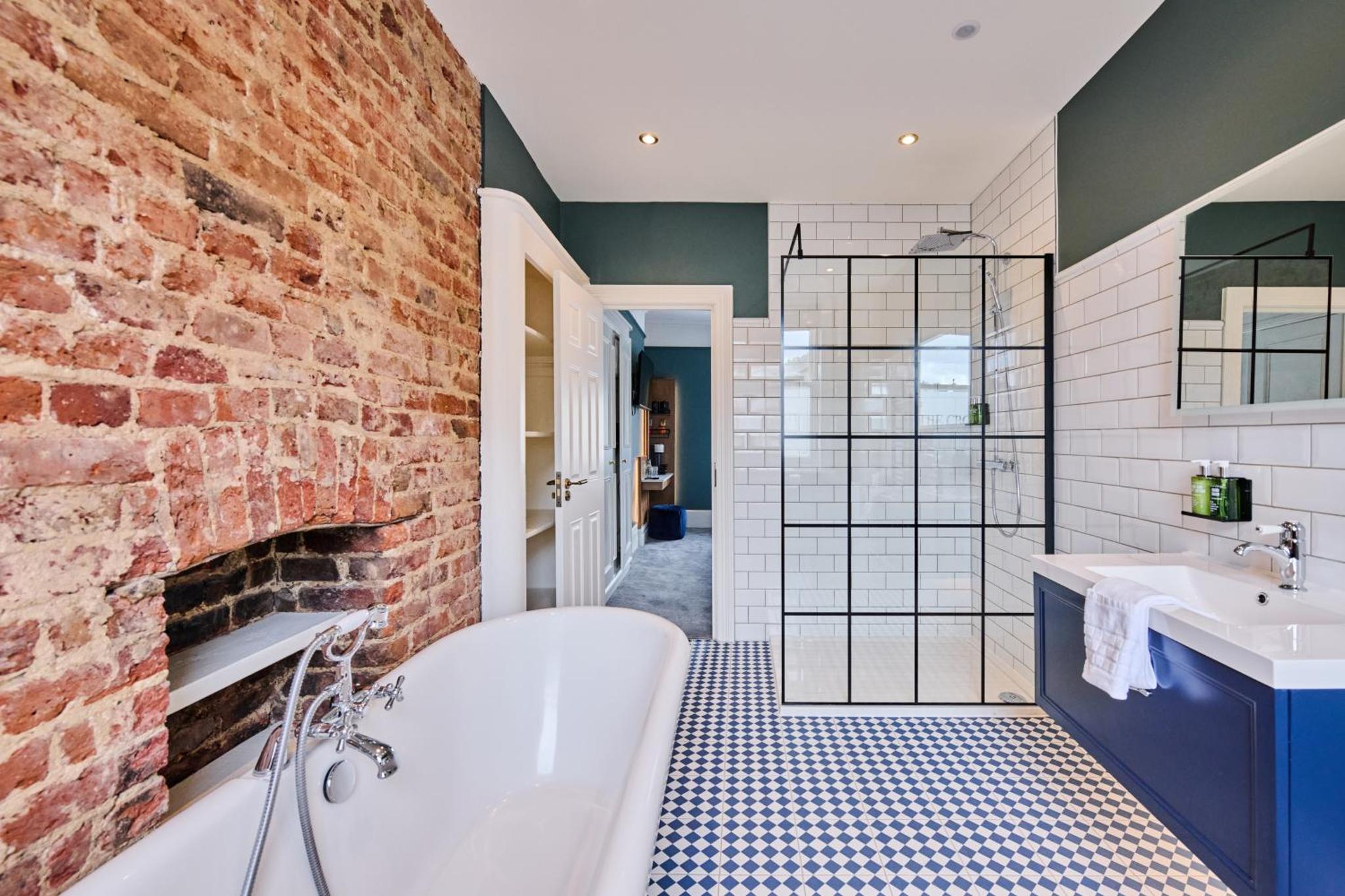 a bathroom with a white tub and a brick wall at The Crown Pub & Guesthouse in London