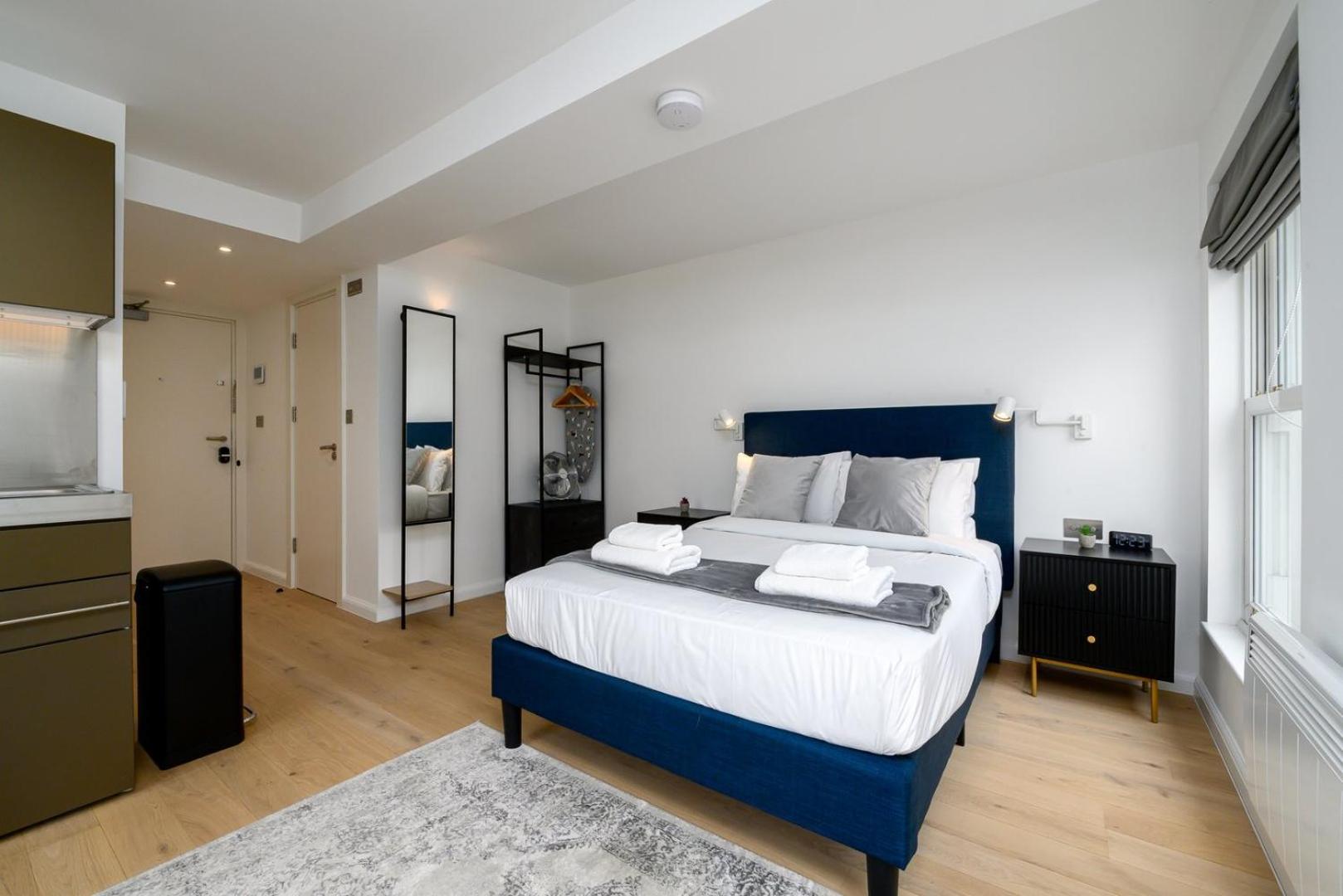 a bedroom with a large bed and a kitchen at GuestReady - Greenwich Park Studios in London