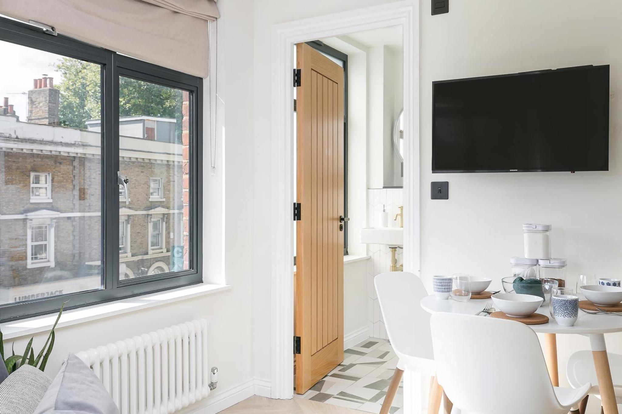 a white dining room with a table and a window at Luxe 2 bed - 20 minutes from Central London in London
