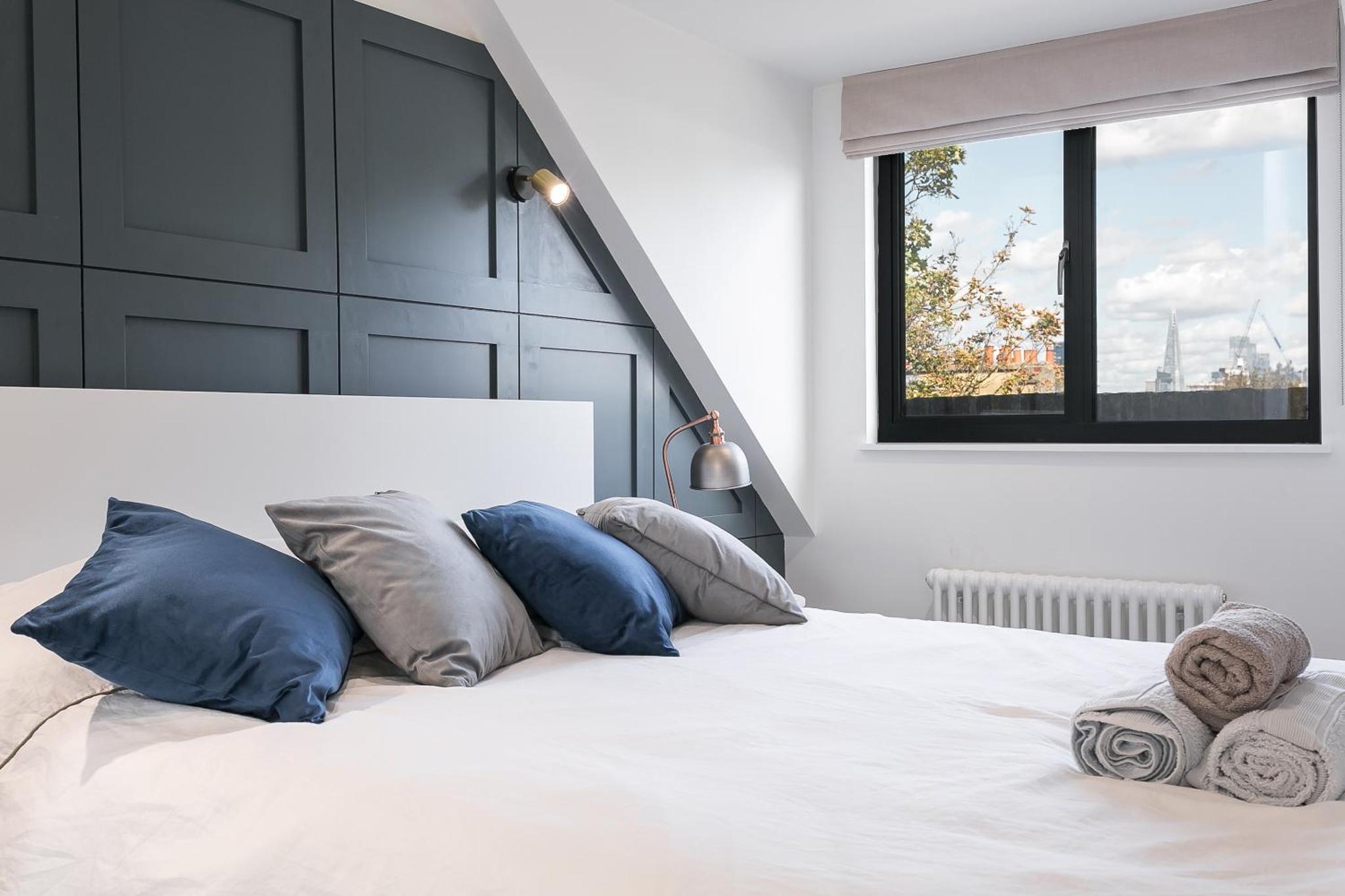 a bedroom with a white bed with pillows and a window at Luxe 2 bed - 20 minutes from Central London in London +1 photo