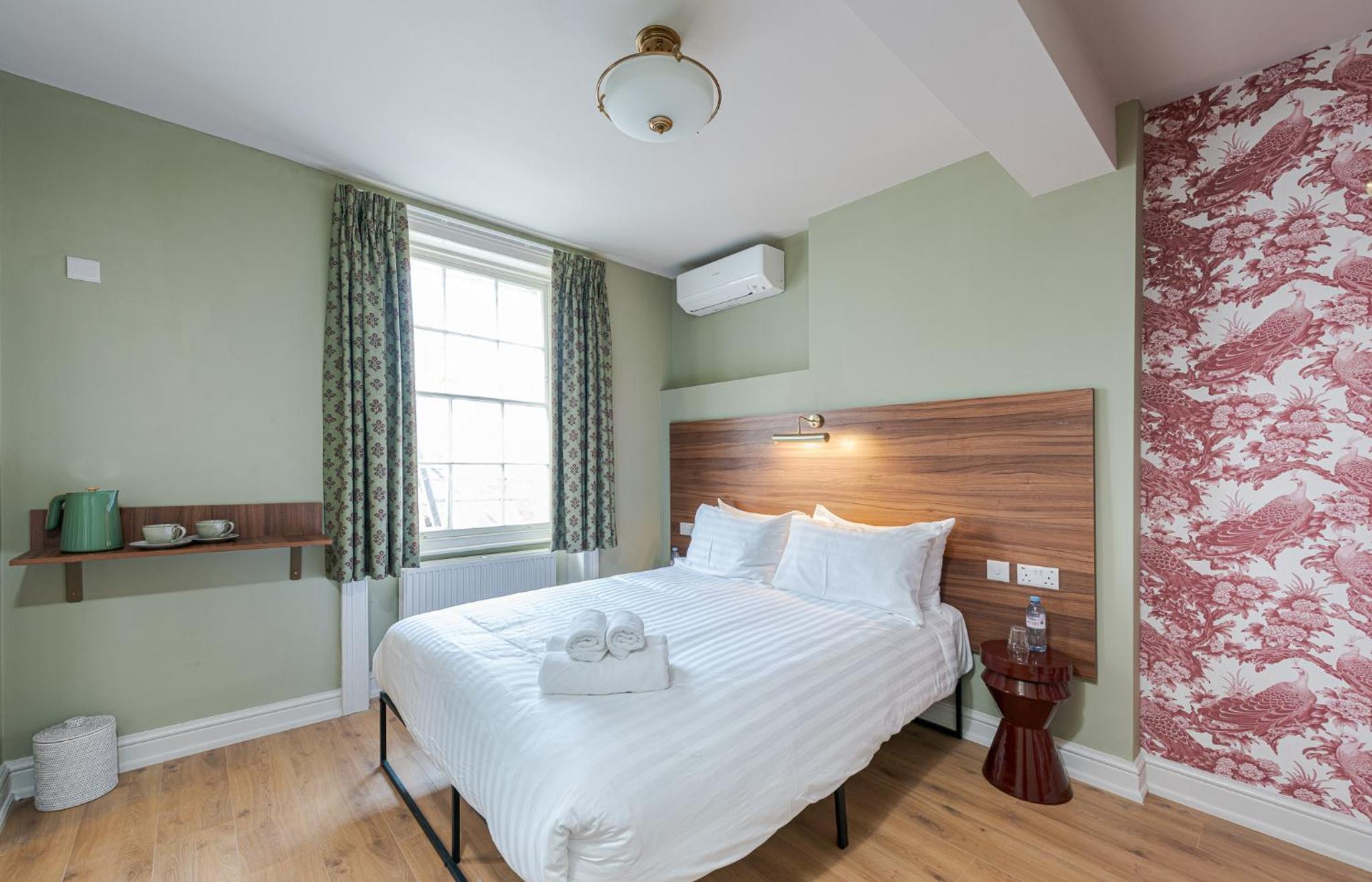 a bedroom with a large bed with a wooden headboard at The Norfolk, Paddington in London