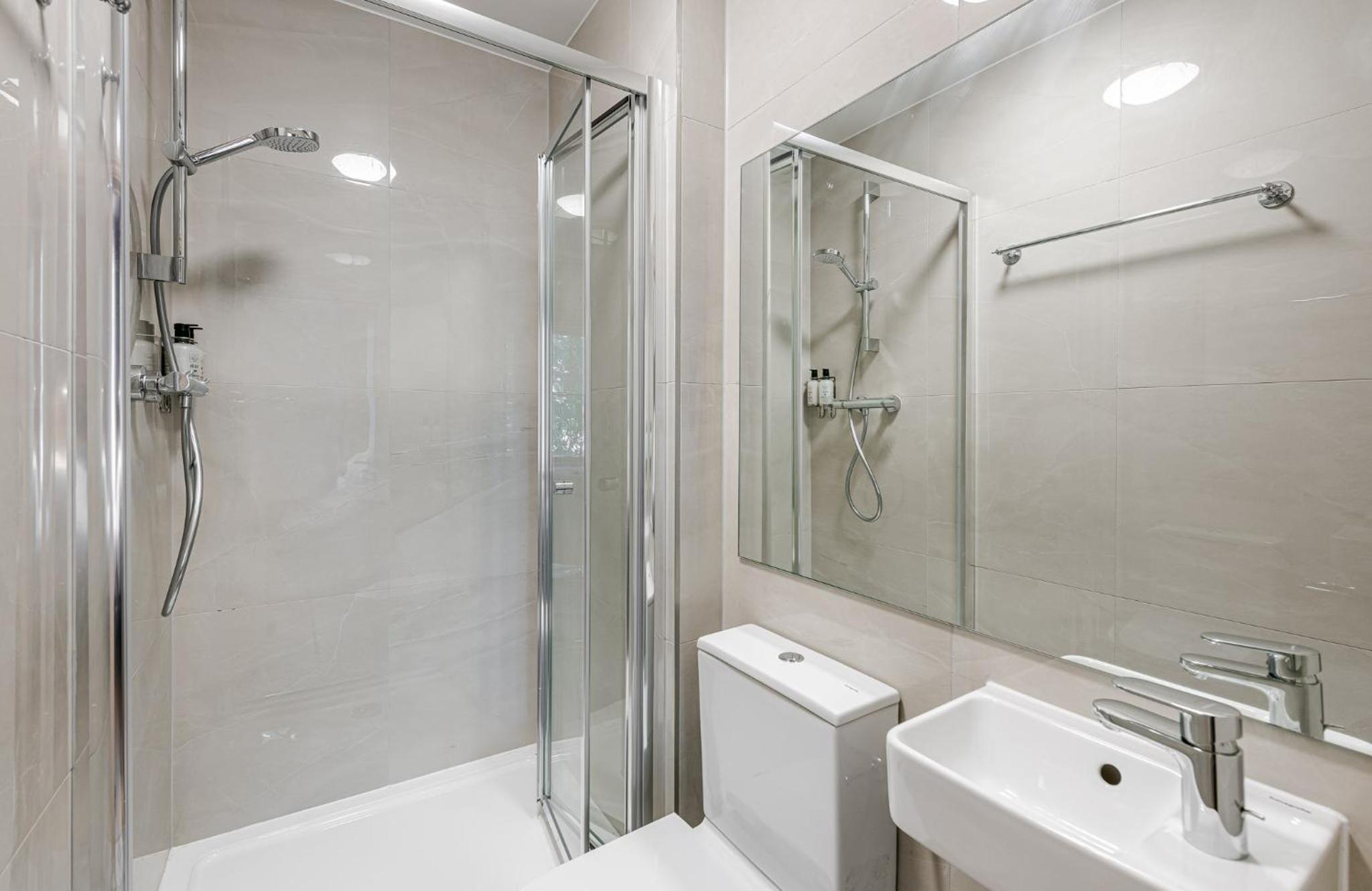 a bathroom with a shower and a toilet and a sink at The Norfolk, Paddington in London