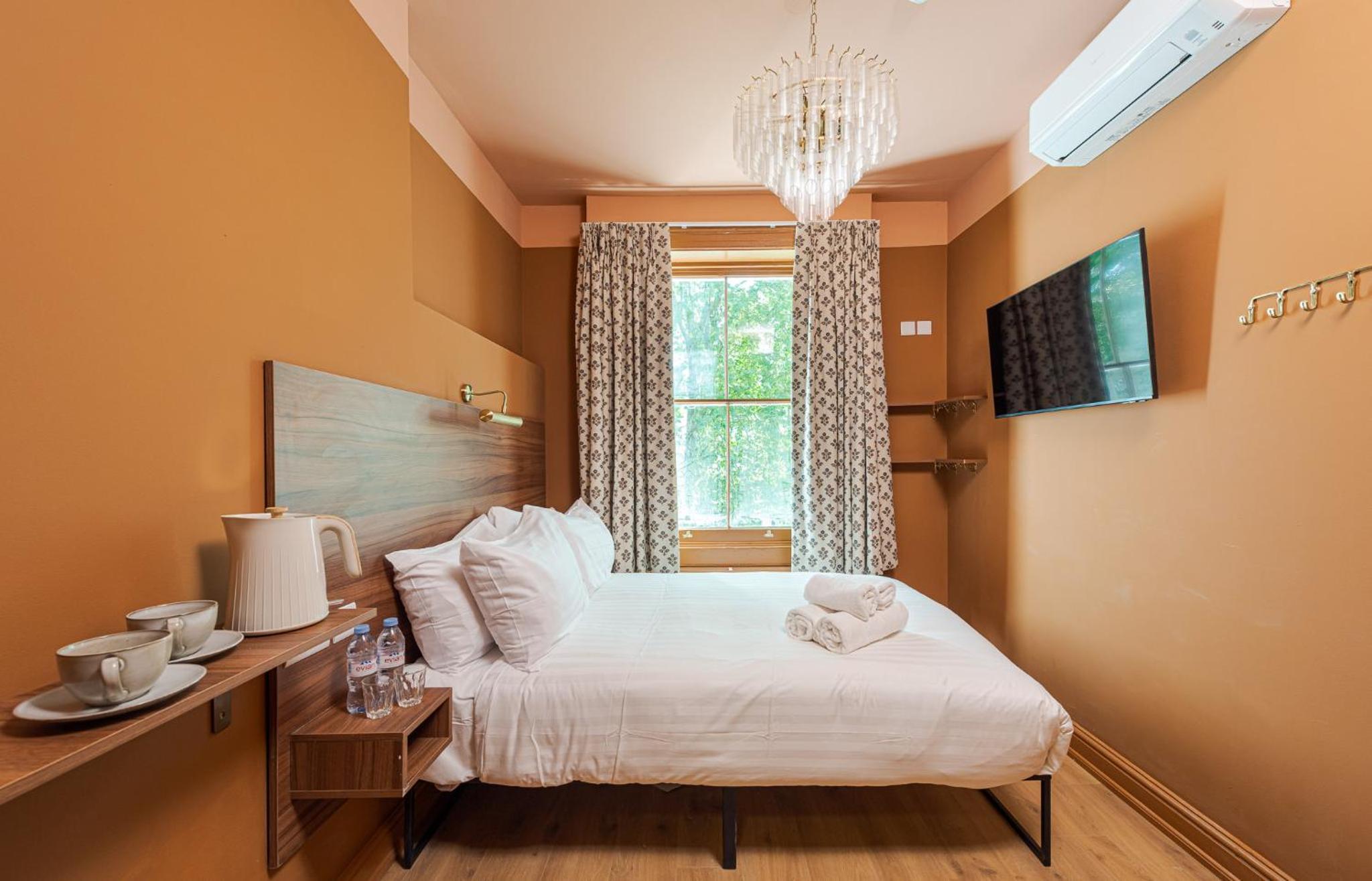 a bedroom with a bed with white sheets and a window at The Norfolk, Paddington in London